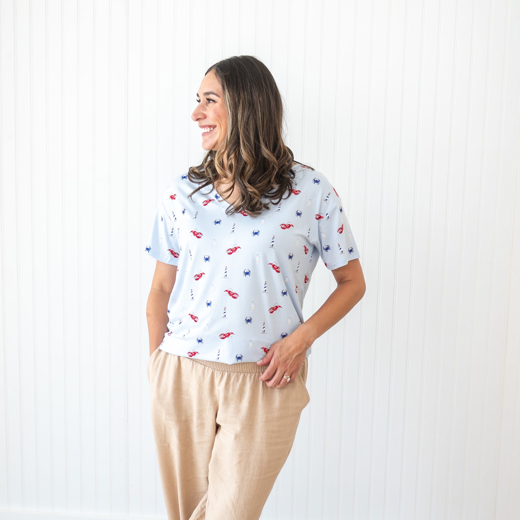 Smiling female model wearing the Women's Relaxed Fit V-Neck in Harbor paired with tan linen pants