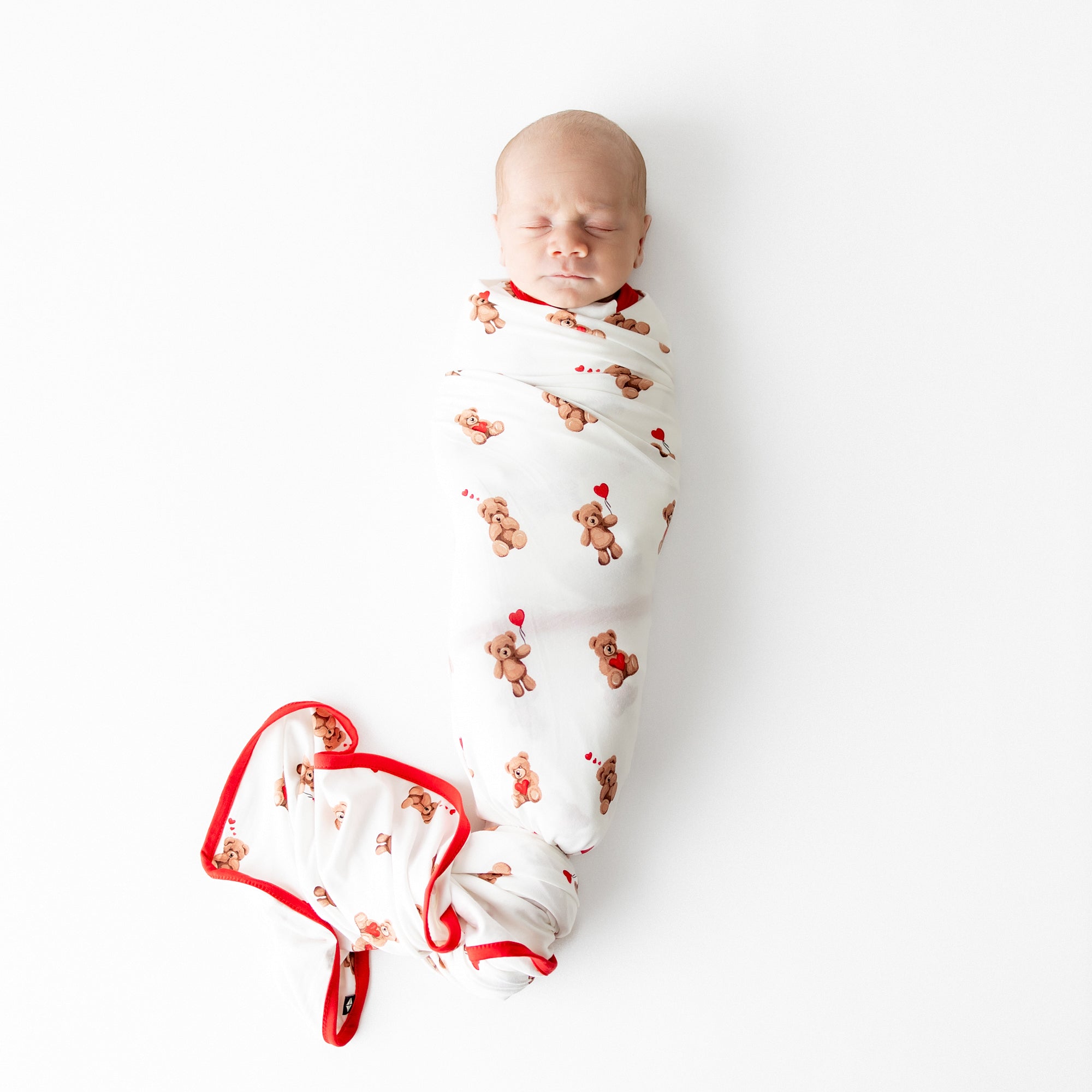Sleeping newborn swaddled in the breathable and stretchy Swaddle Blanket in Bear Hearts