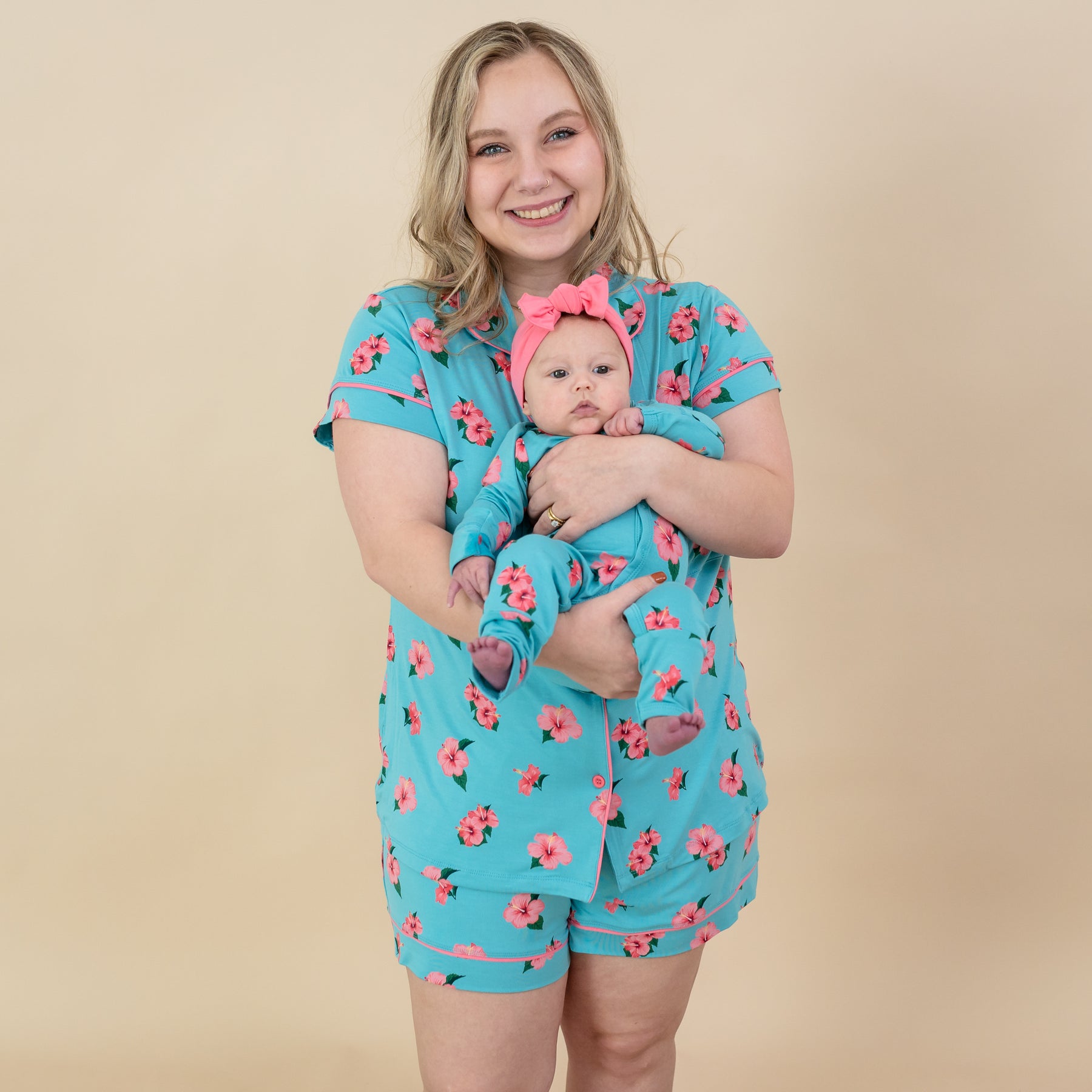 Woman modeling Kyte Short Sleeve Pajama Set in Hibiscus while holding baby in matching Hibiscus outfit