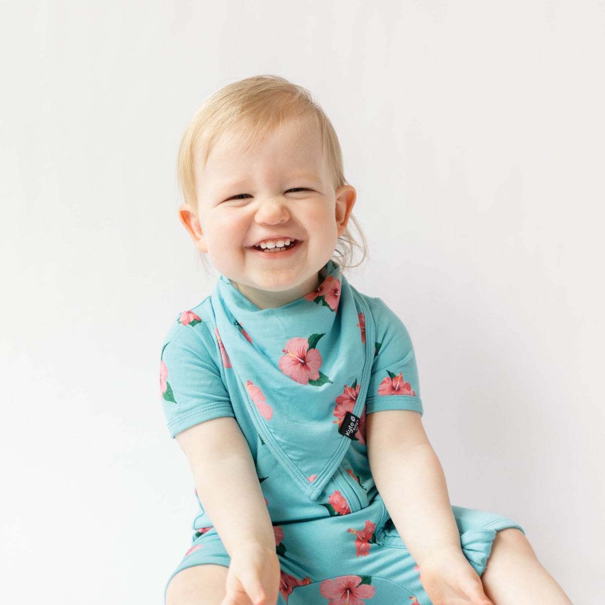 toddler wearing zippered shortall romper in hibiscus  and bib