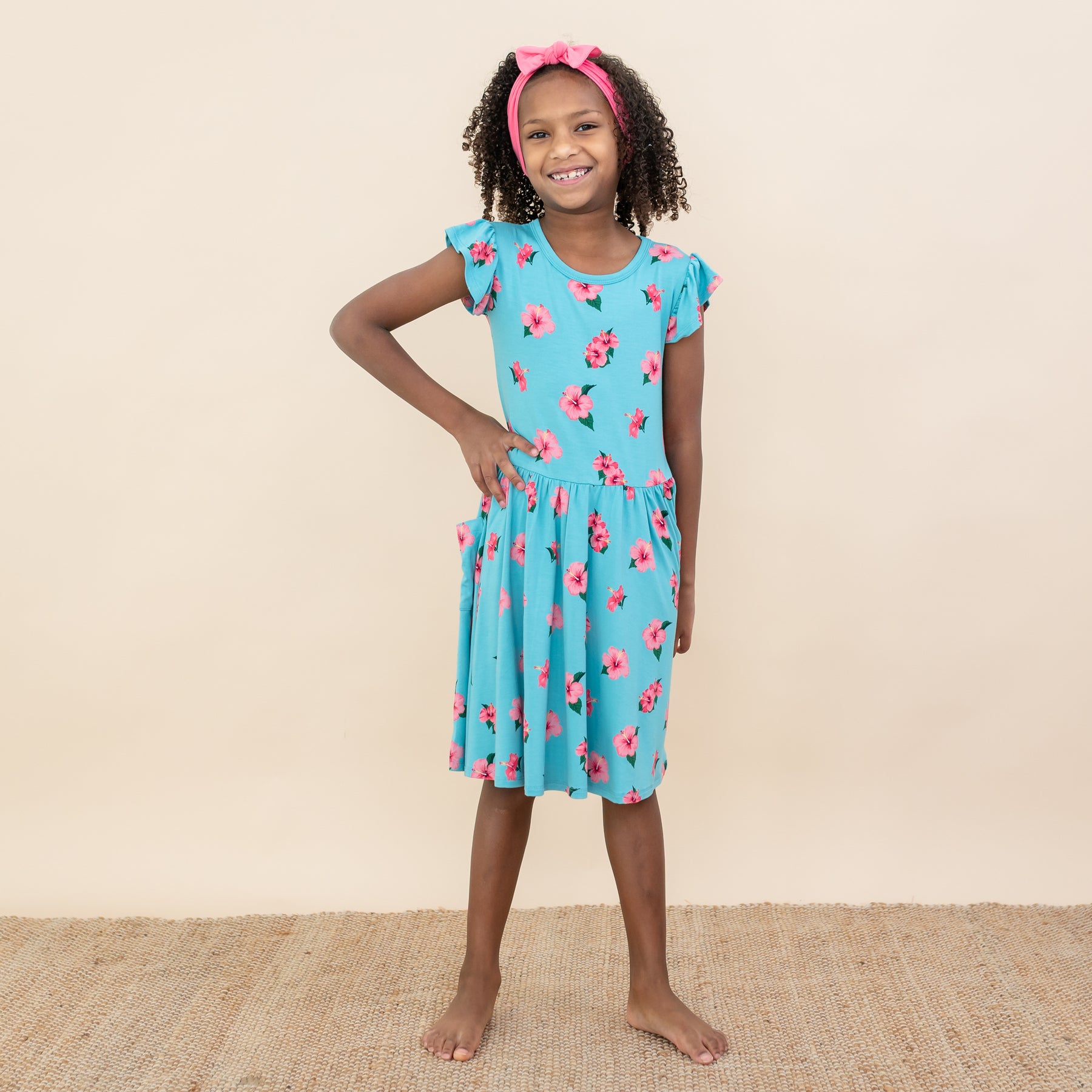 Child modeling Kyte Pocket Dress in Hibiscus with Guava Bow