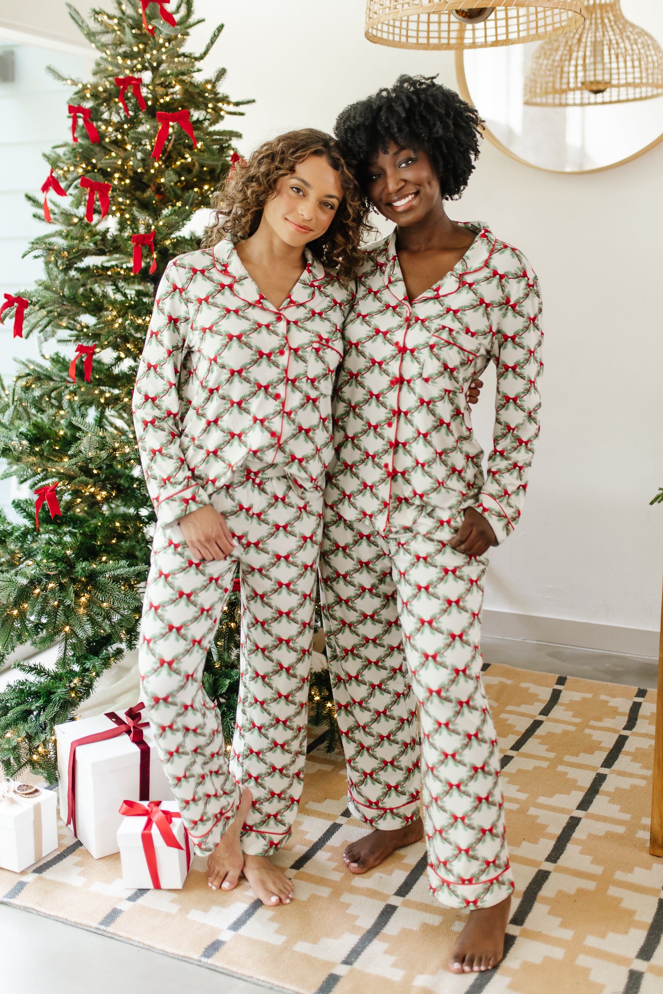 Two female models standing side by side both wearing the Long-Sleeved Women's Pajama Set in Holiday Bow
