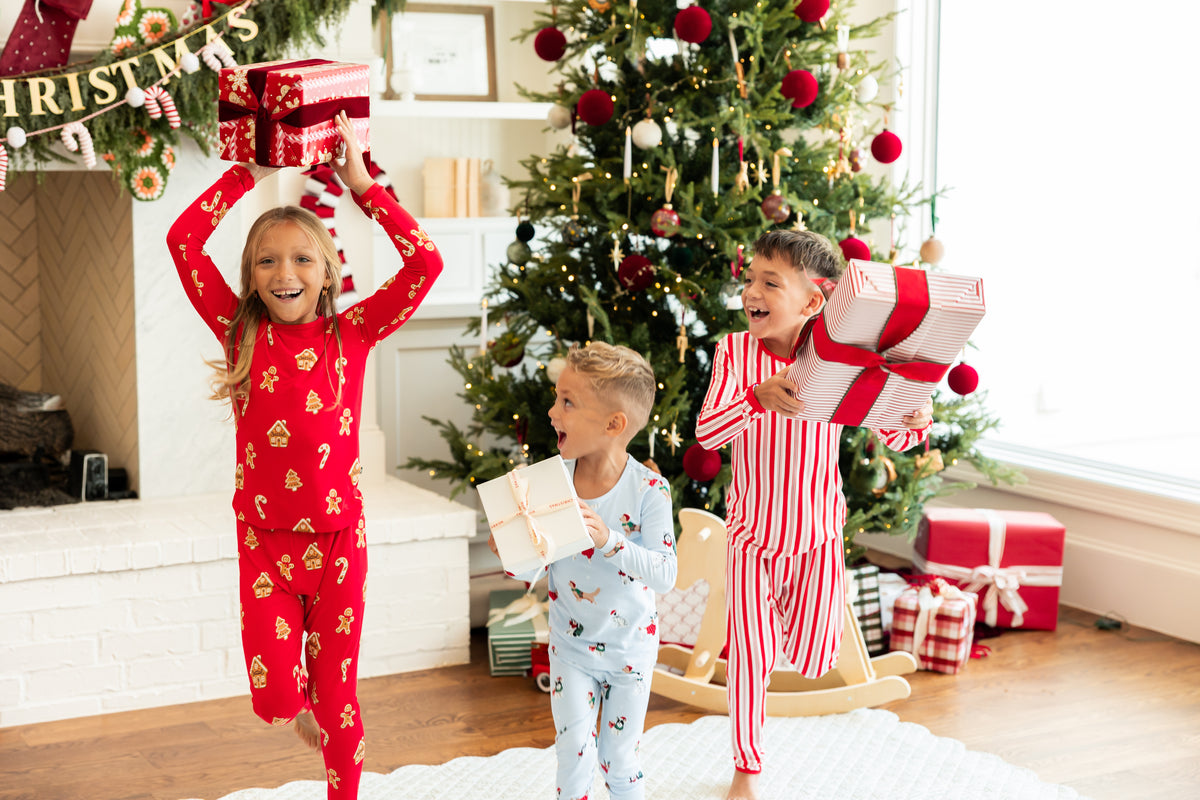 3 kids running with christmas presents in kyte baby christmas pajamas