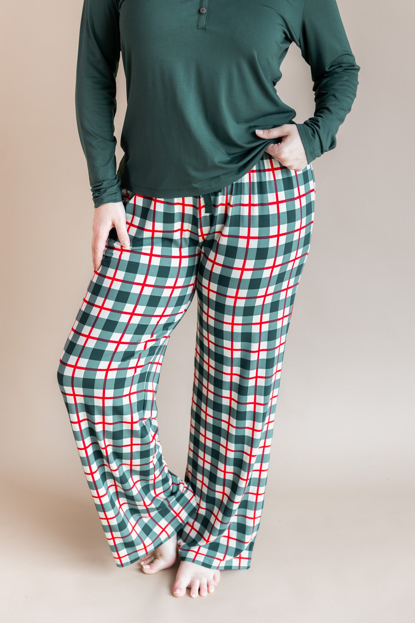 Woman wearing Women's lounge pants in Holiday plaid over cypress color t-shirt on a beige background