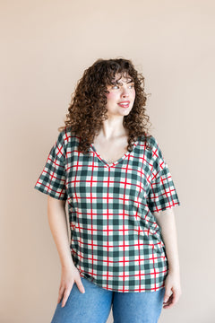 Modal posing in women's V-Neck Tee in Holiday Plaid over blue jeans on a beige background