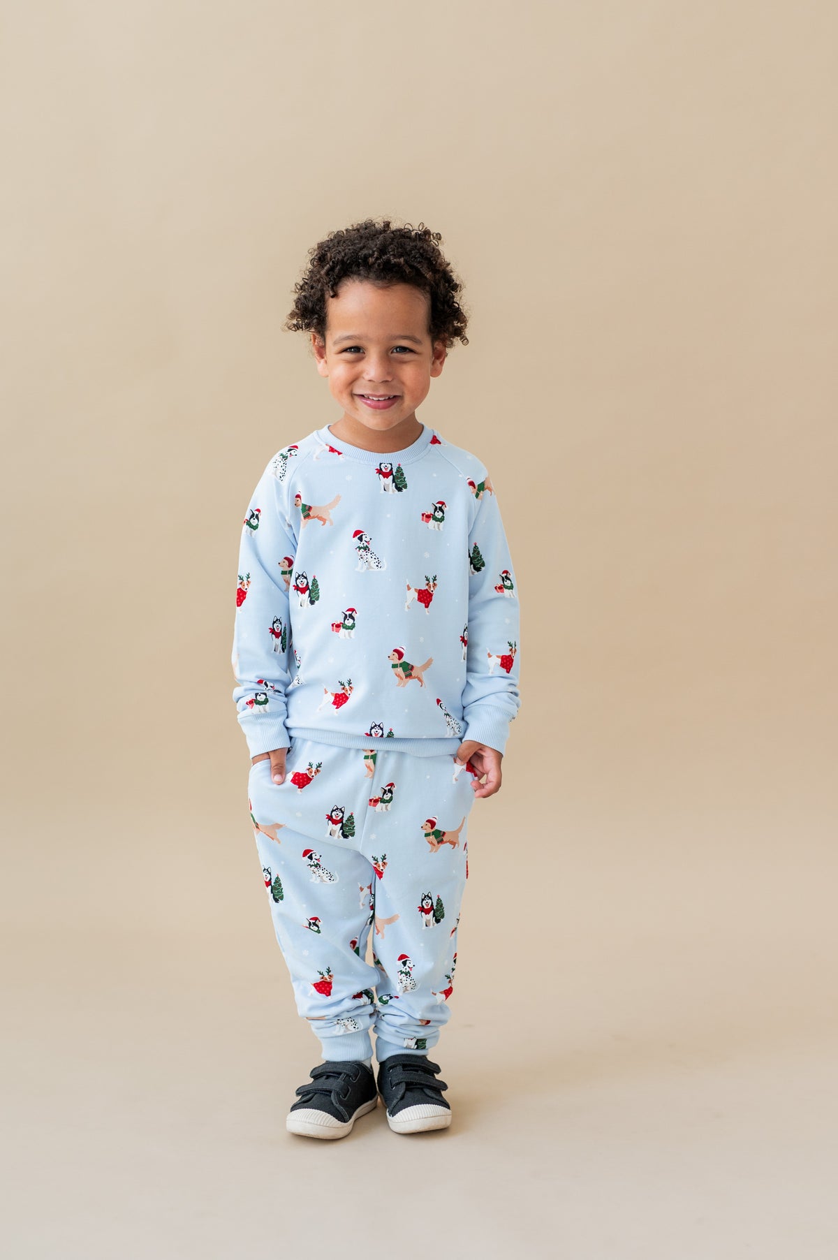 Boy smiling in Long Sleeve Jogger Set in Holiday Pups print on a beige background