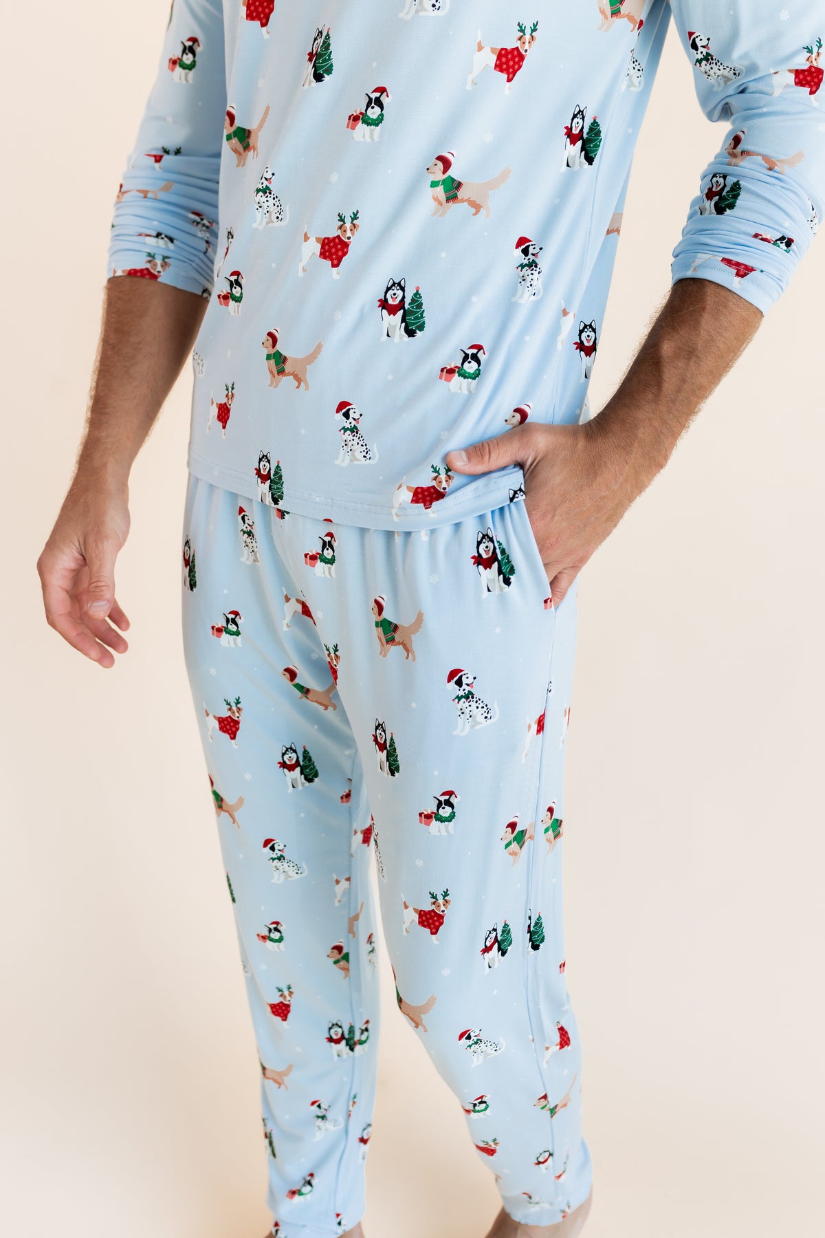 Man showcasing the pockets on Men's Jogger Set in Holiday Pups print on a beige background