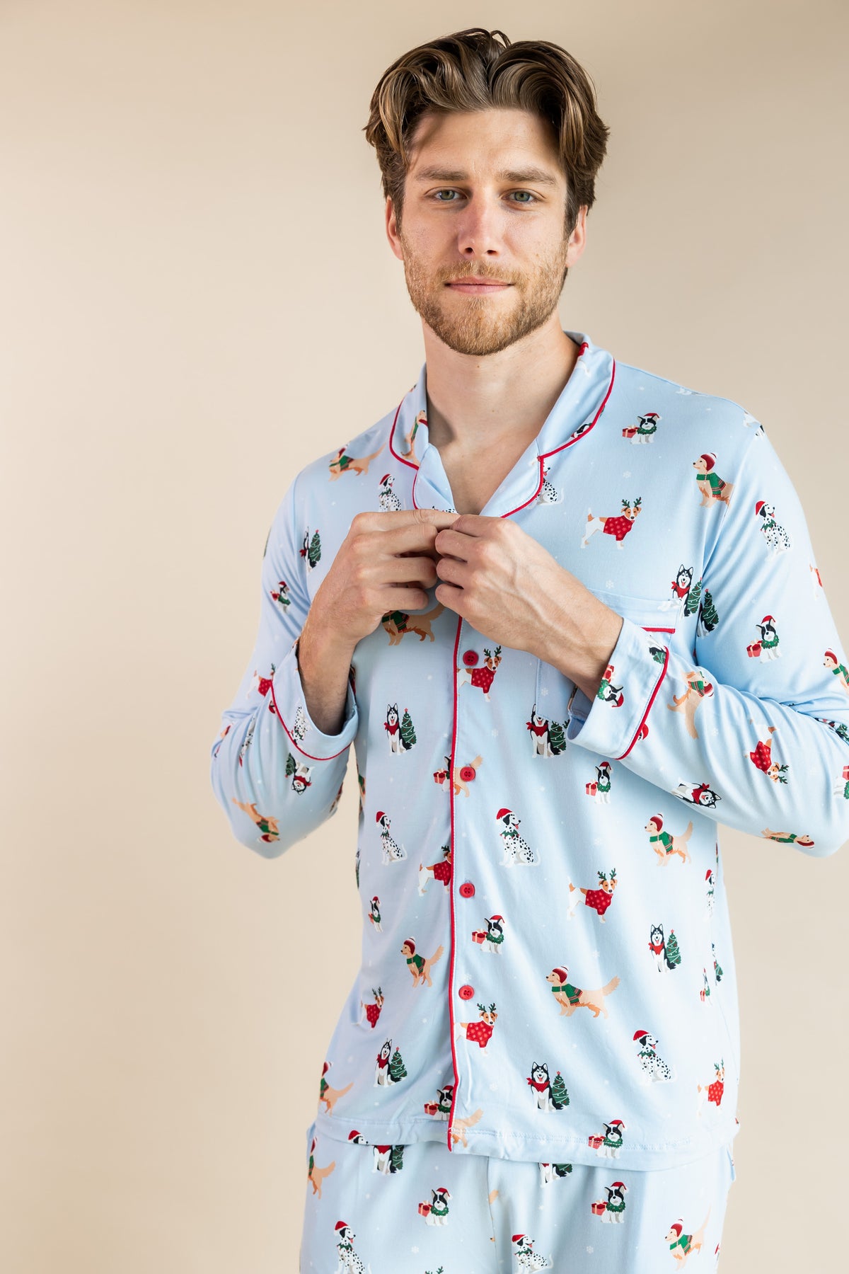 Man wearing Men's Long Sleeve Pajama Set in Holiday Pups on a beige background