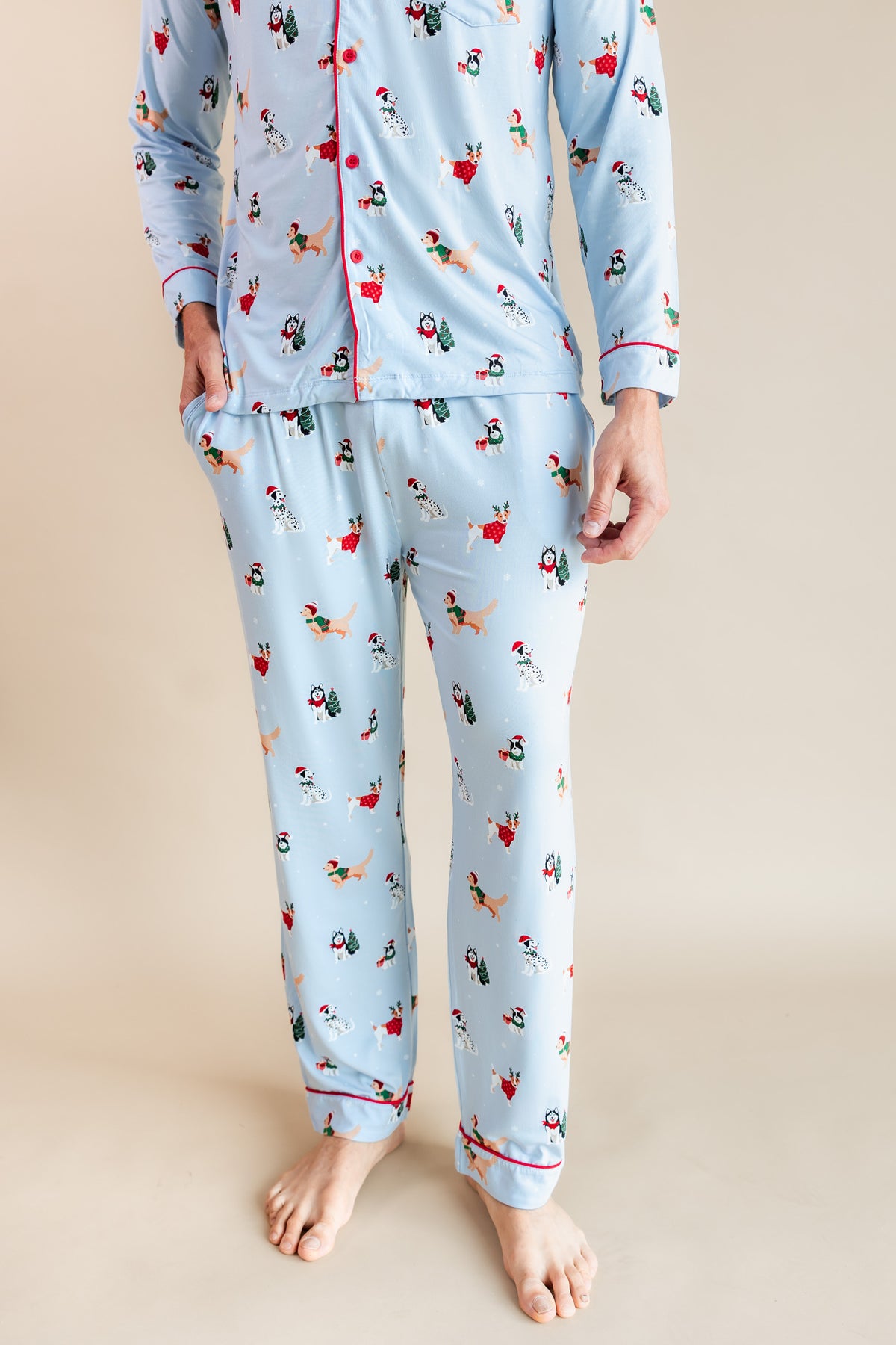 Man showcasing the front side of Men's Long Sleeve Pajama Set in Holiday Pups print on a beige background