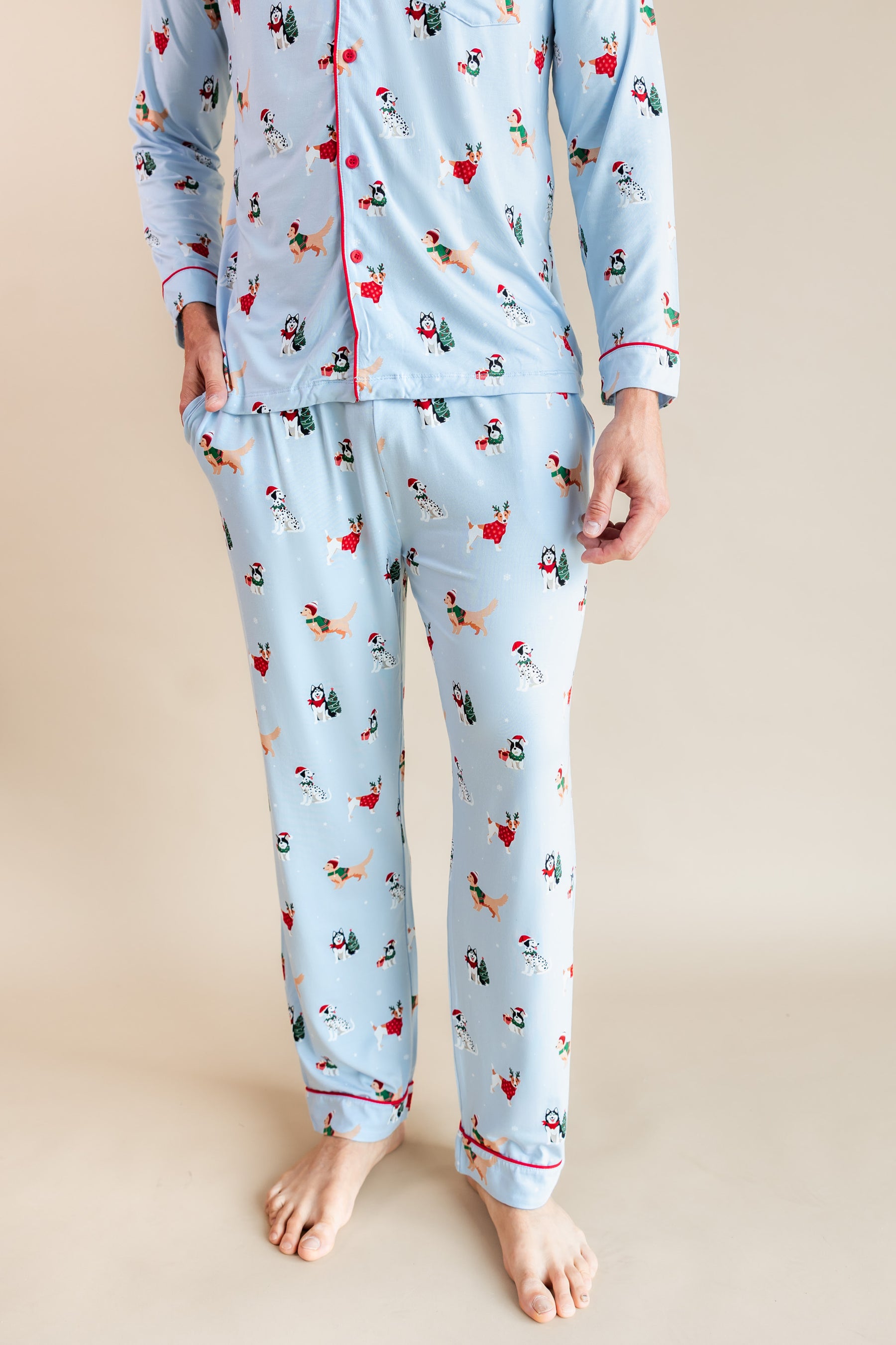 Man showcasing the front side of Men's Long Sleeve Pajama Set in Holiday Pups print on a beige background