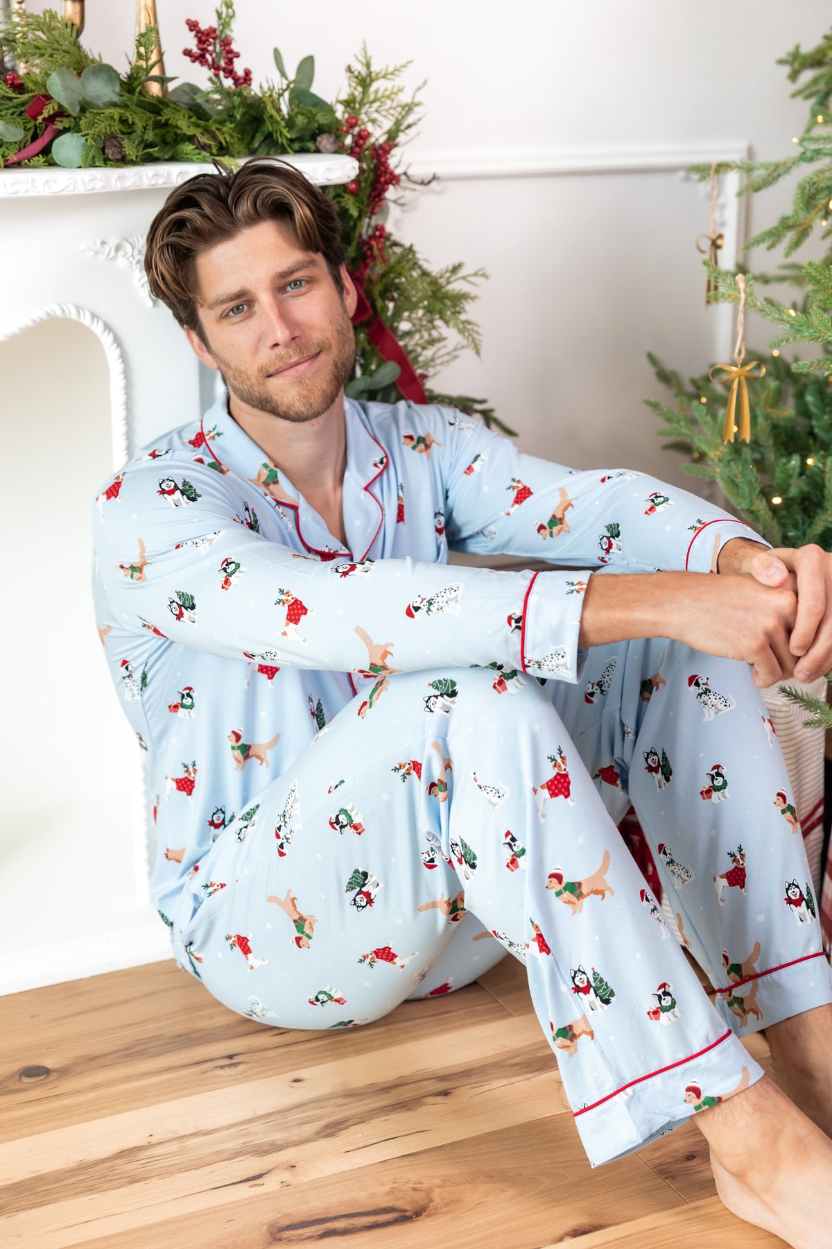 Man sitting on wooden floor while wearing Men's Long Sleeve Pajama Set in Holiday Pups print