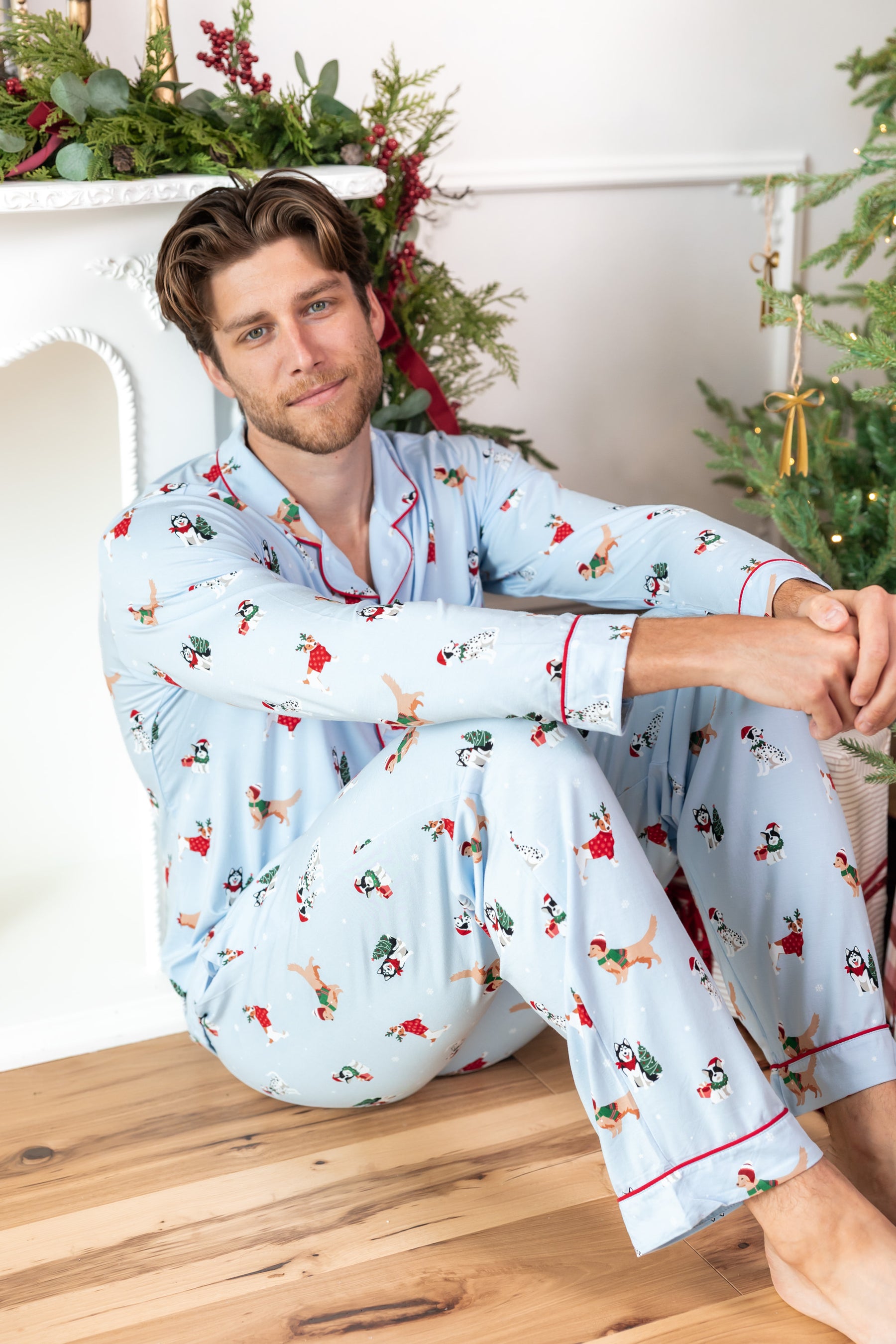 Man sitting on wooden floor while wearing Men's Long Sleeve Pajama Set in Holiday Pups print