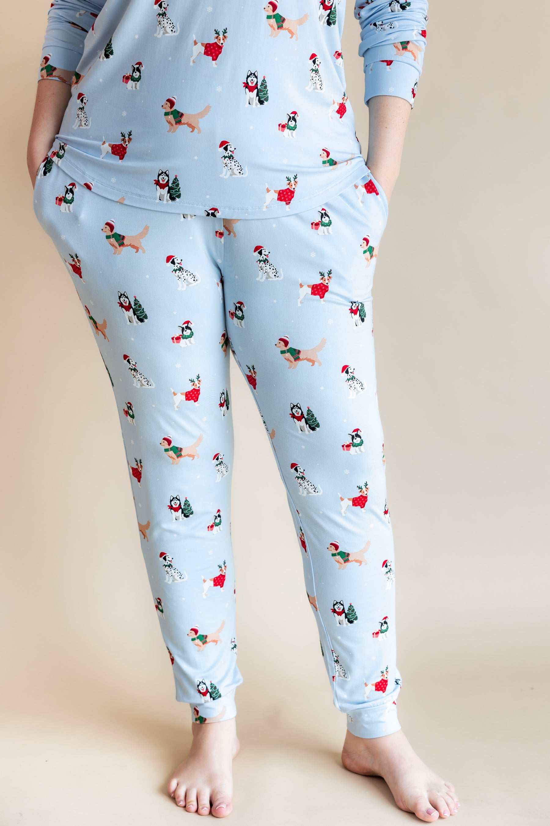 Woman showcasing the pockets on Women's Jogger Pajama Set in Holiday Pups print on a beige background