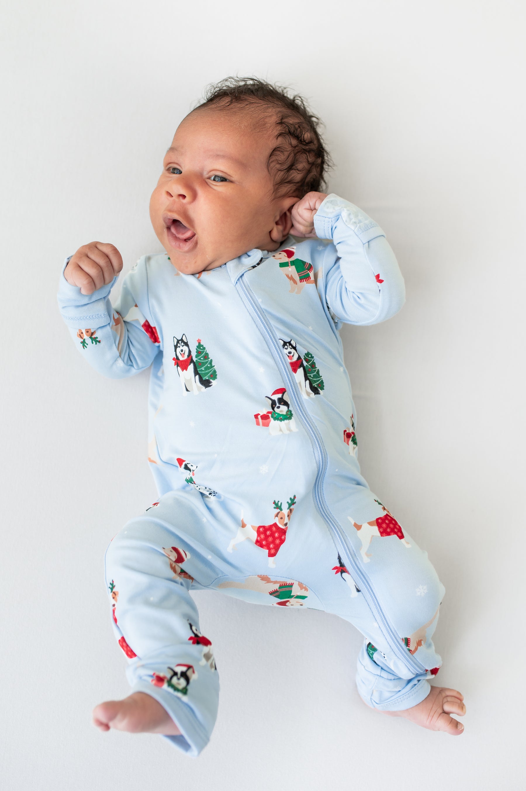 Baby wearing Zippered Romper in Holiday Pups print on a white background