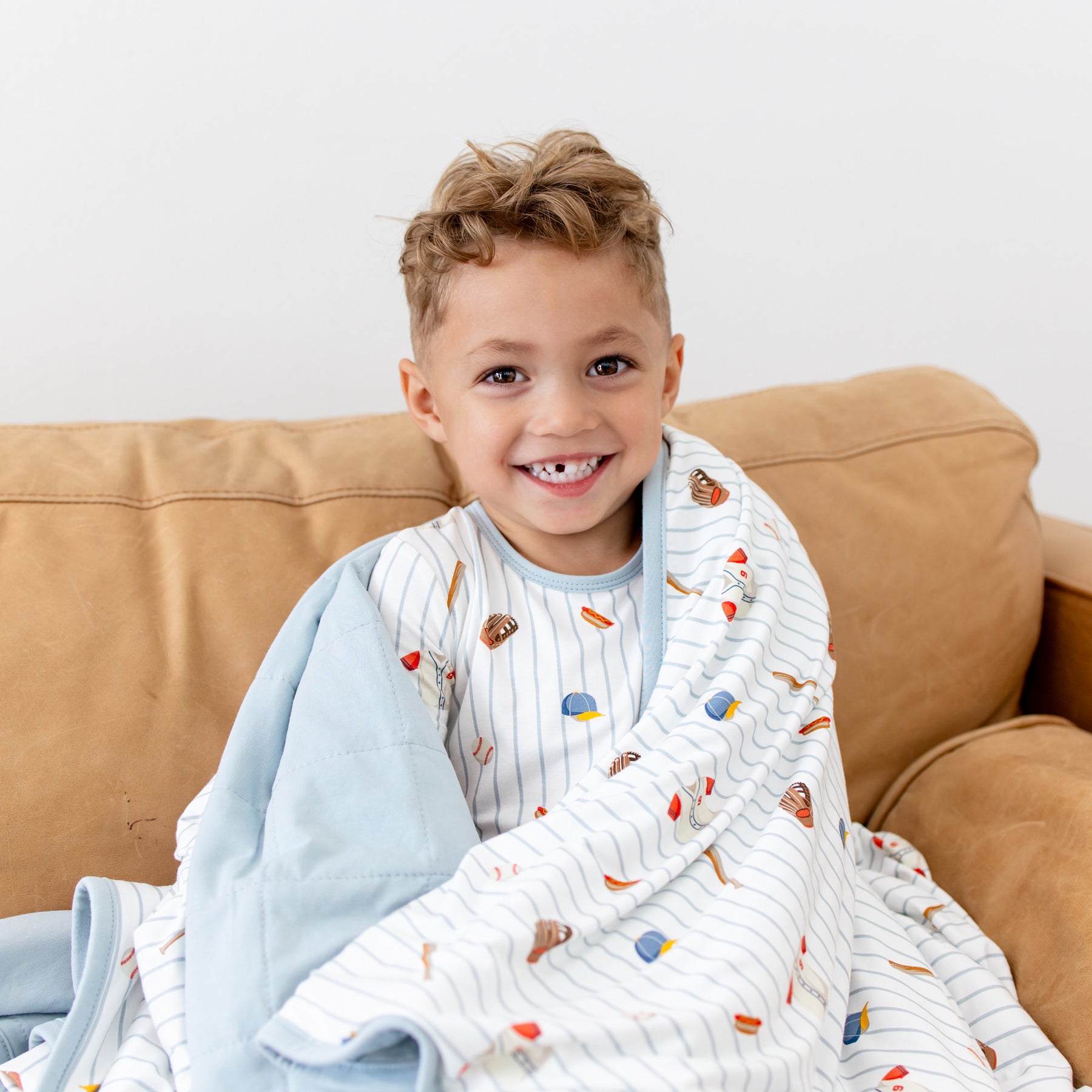 Close up of young boy with the Youth Blanket in Home Run 1.0 wrapped around his shoulders wearing matching pajamas
