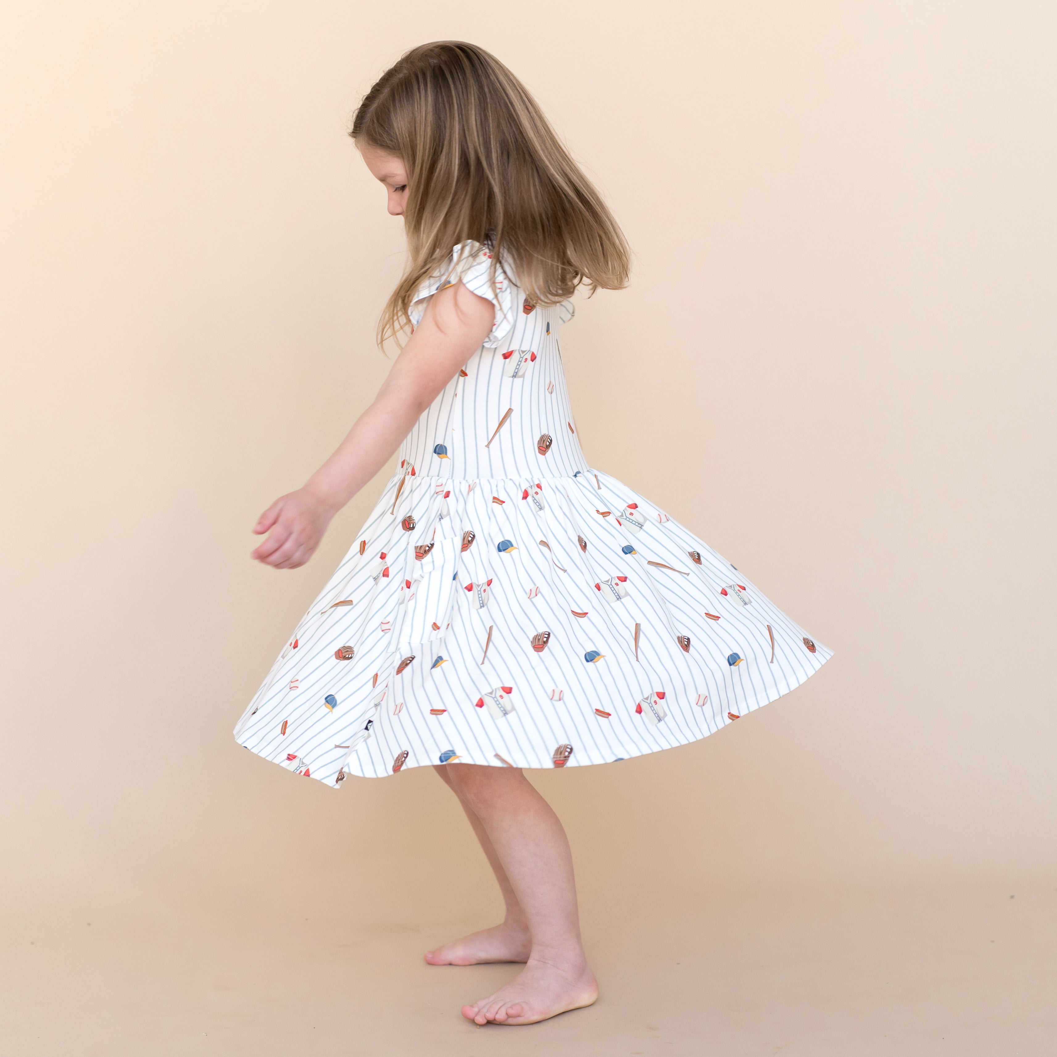 Young girl twirling wearing the Pocket Dress in Home Run