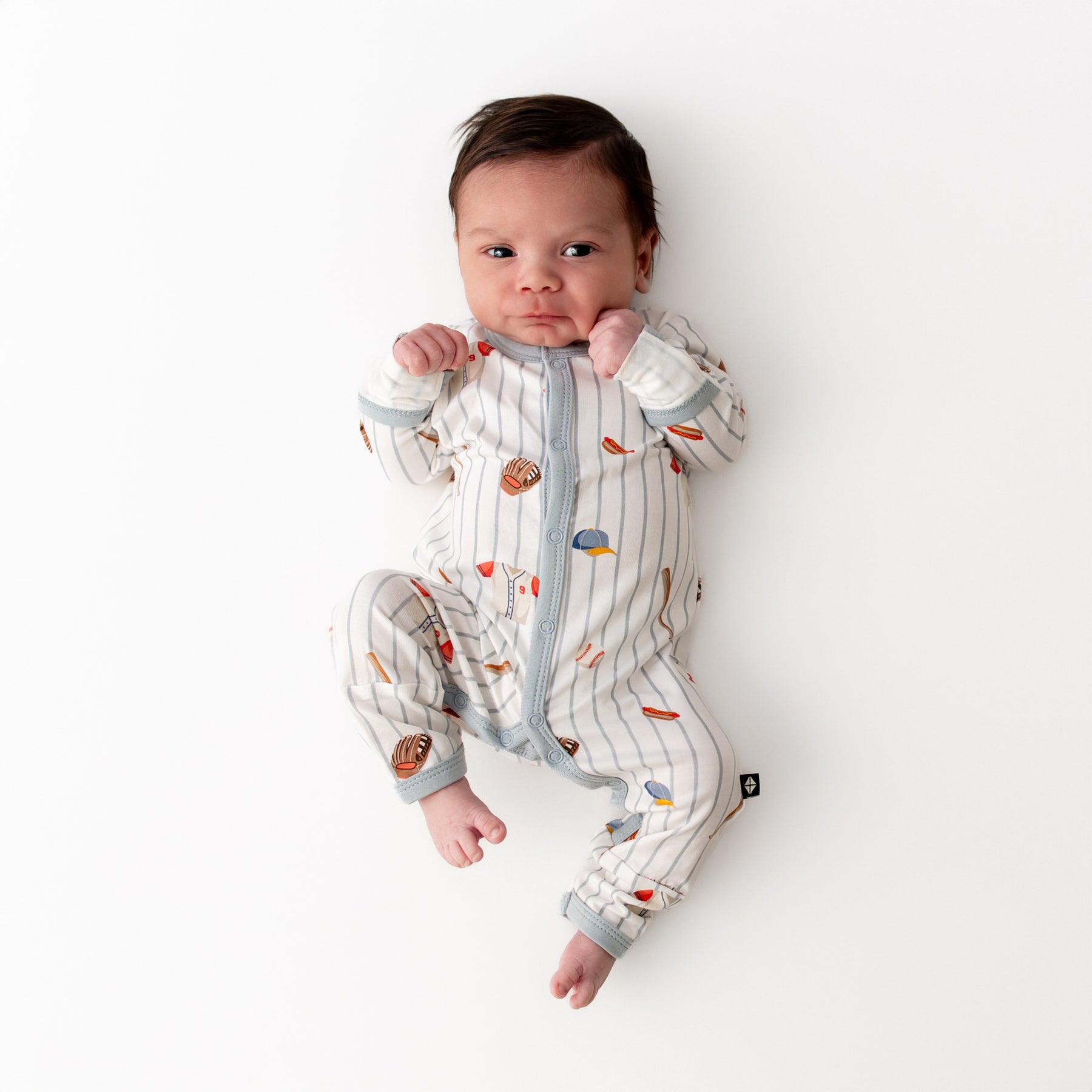 Newborn laying on a white surface wearing the Romper in Home Run