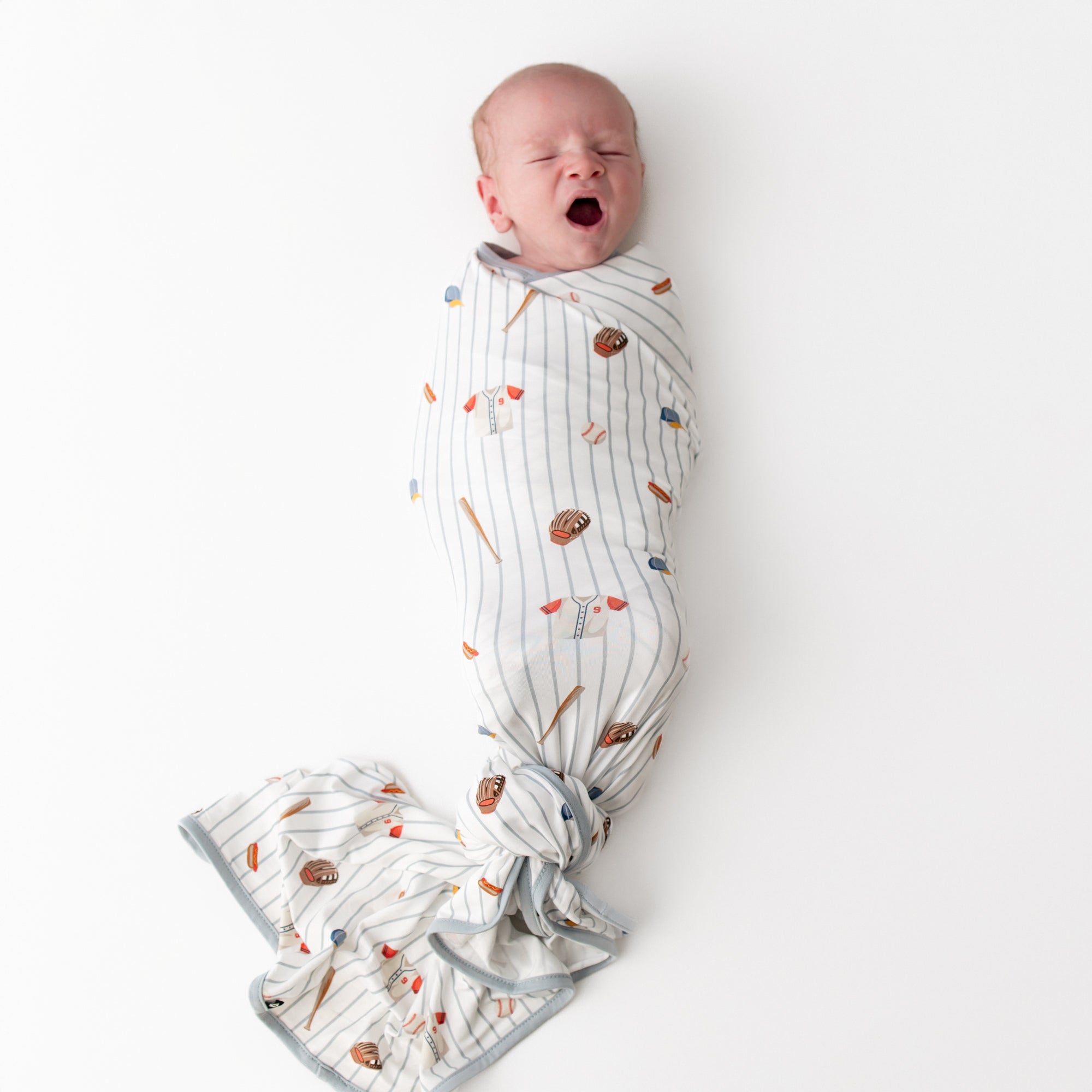 Yawning newborn swaddled in the Swaddle Blanket in Home Run