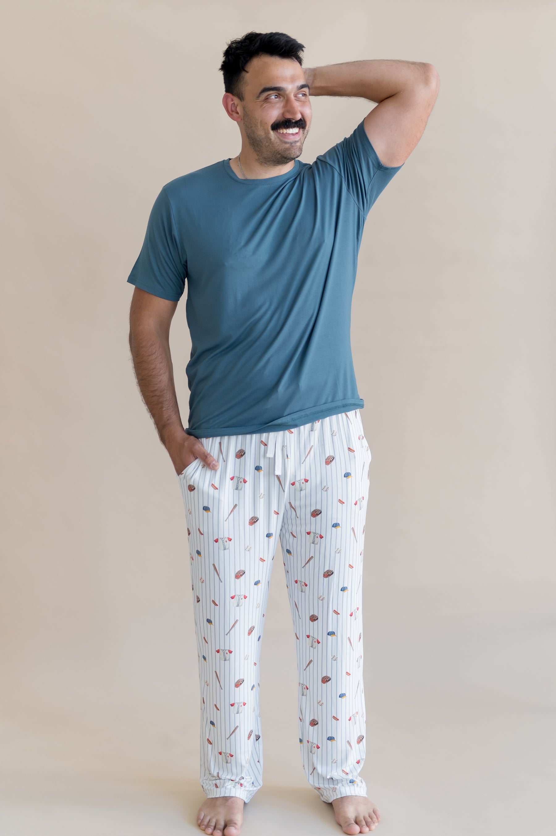 Male model posing wearing the Men's Lounge Pants in Home Run with a muted dark blue shirt