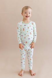 Child wearing a green and white striped long sleeve pajama set with colorful Harry Potter patterns on a beige background