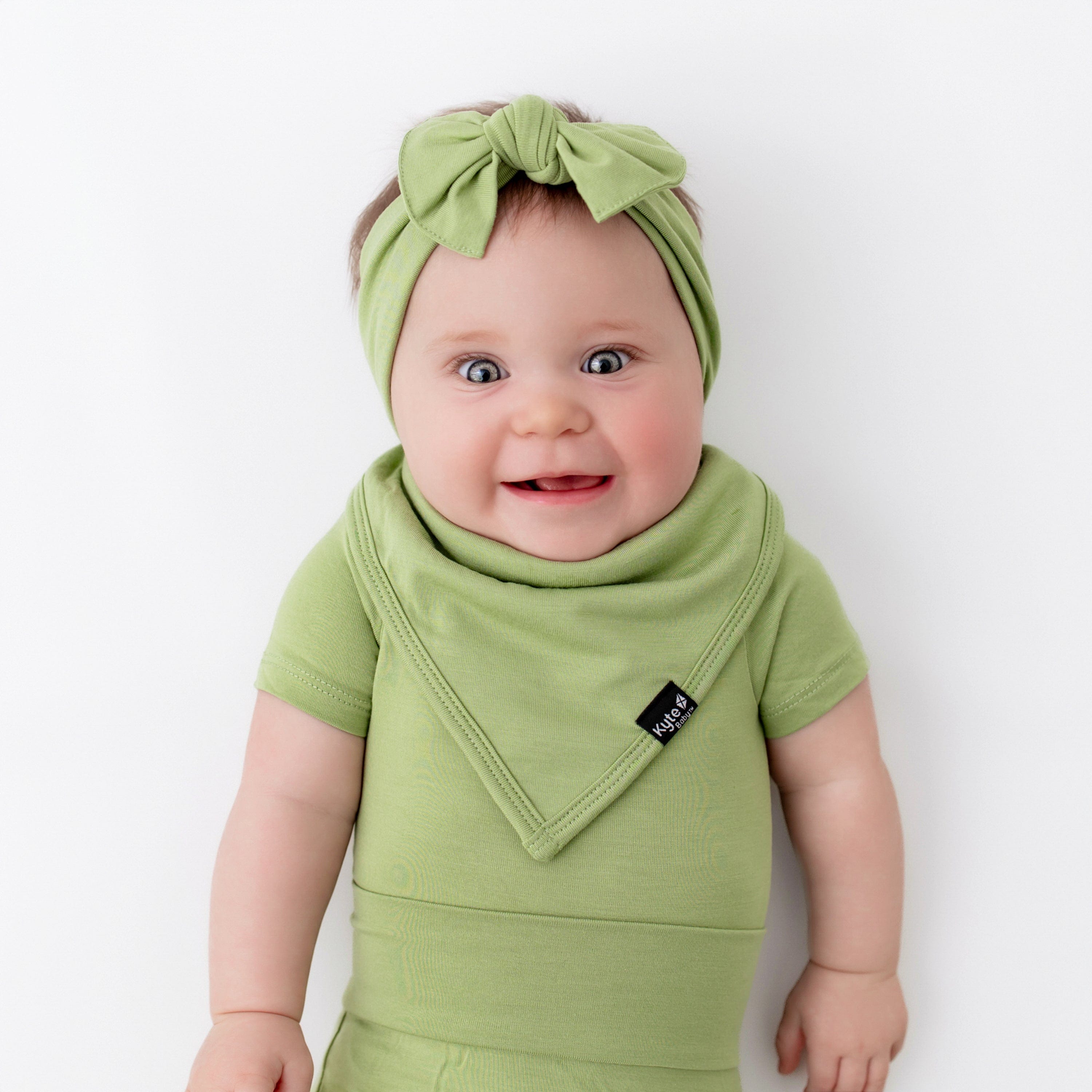 baby wearing kyte baby bodysuit in honu and matching bib and bow