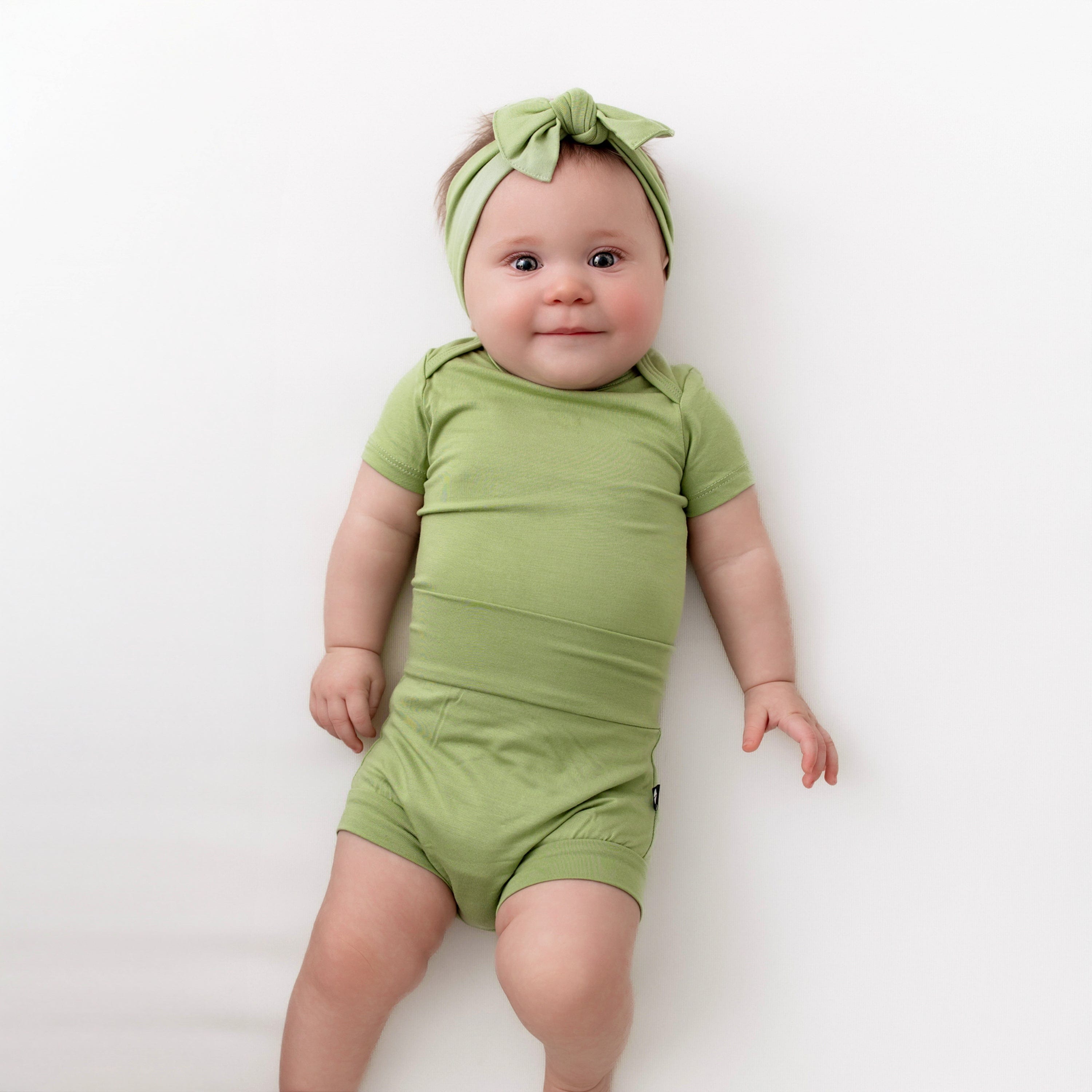 baby wearing kyte baby bodysuit in honu and matching bib and bummies