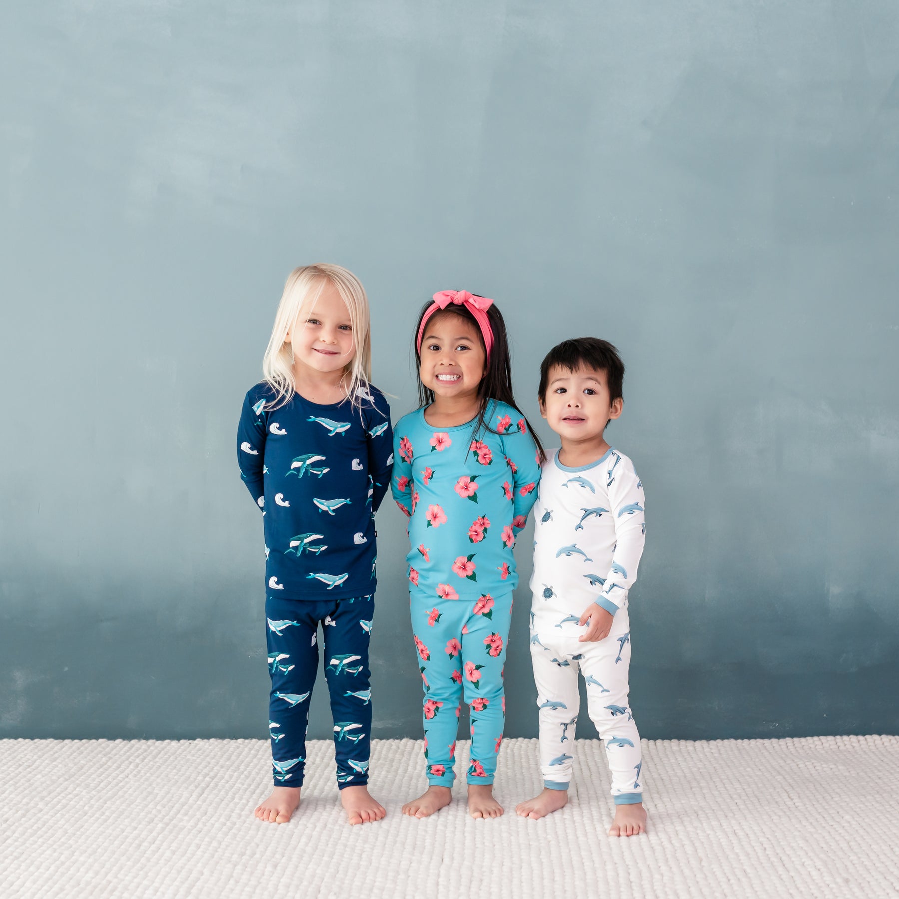 3 toddlers wearing Kyte Long Sleeve Pajamas in Humpback, Hibiscus and Dolphin