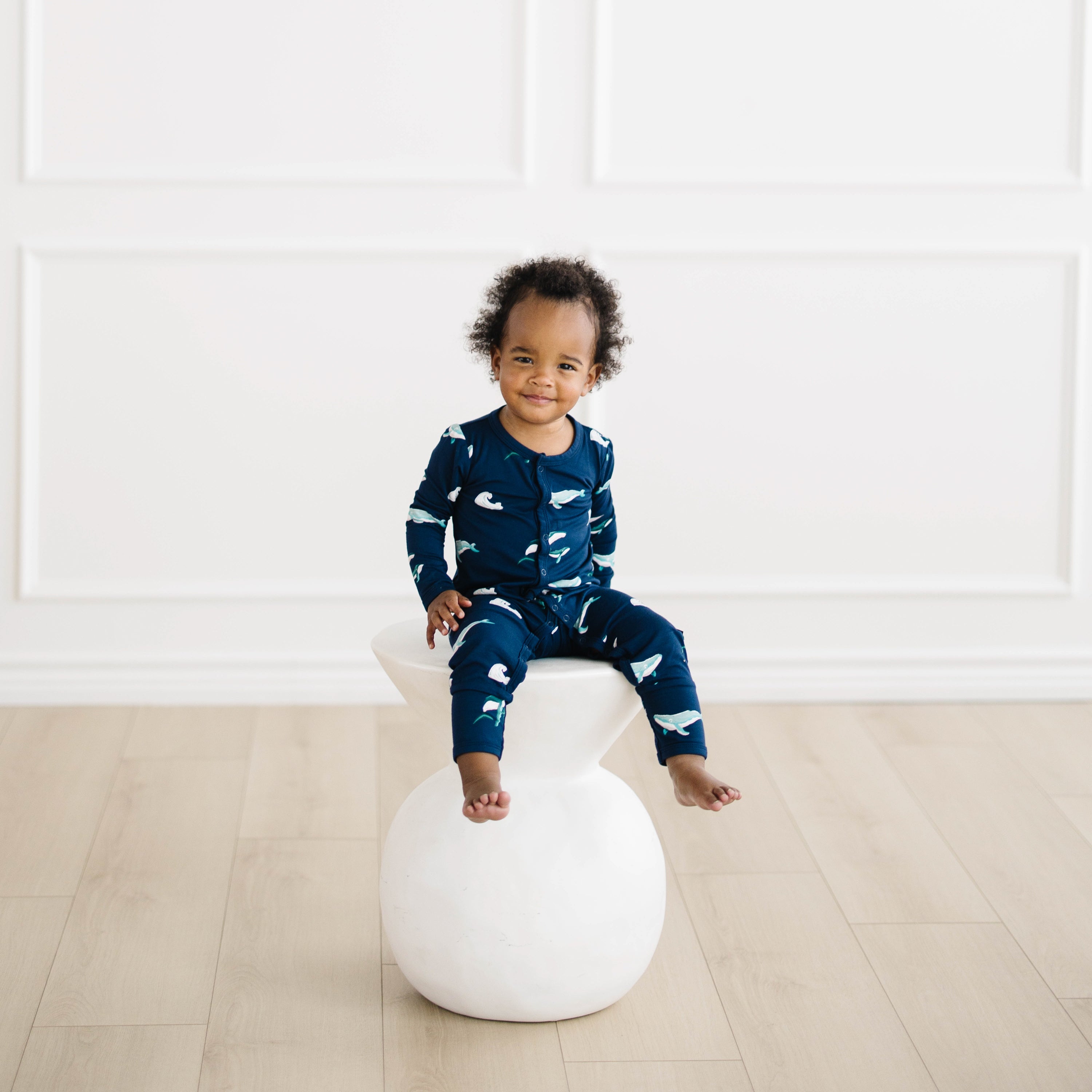 toddler sitting and wearing snap romper in humpback