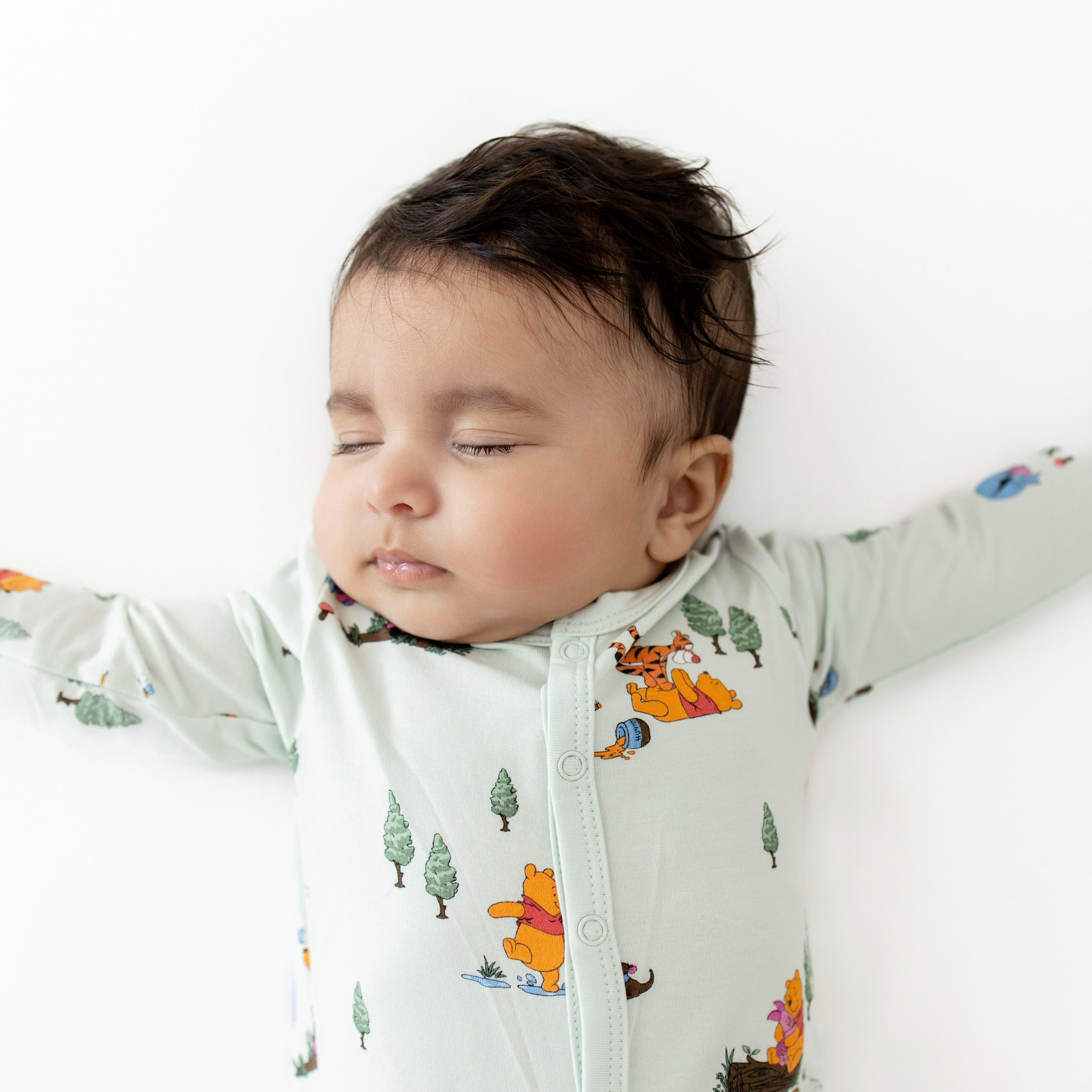 Close up of sleeping baby wearing the Footie in Winnie the Pooh Hundred Acre Wood
