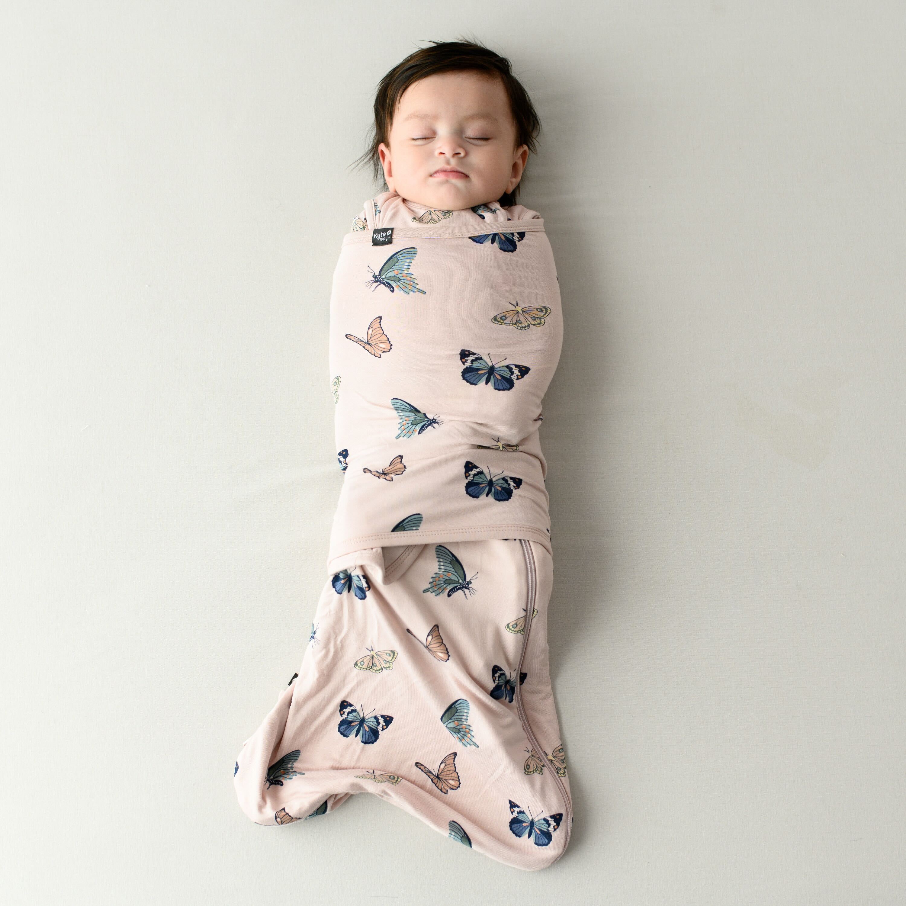Infant model sleeping while swaddled in the 0.5 TOG Sleep Bag Swaddler in Blush Butterfly