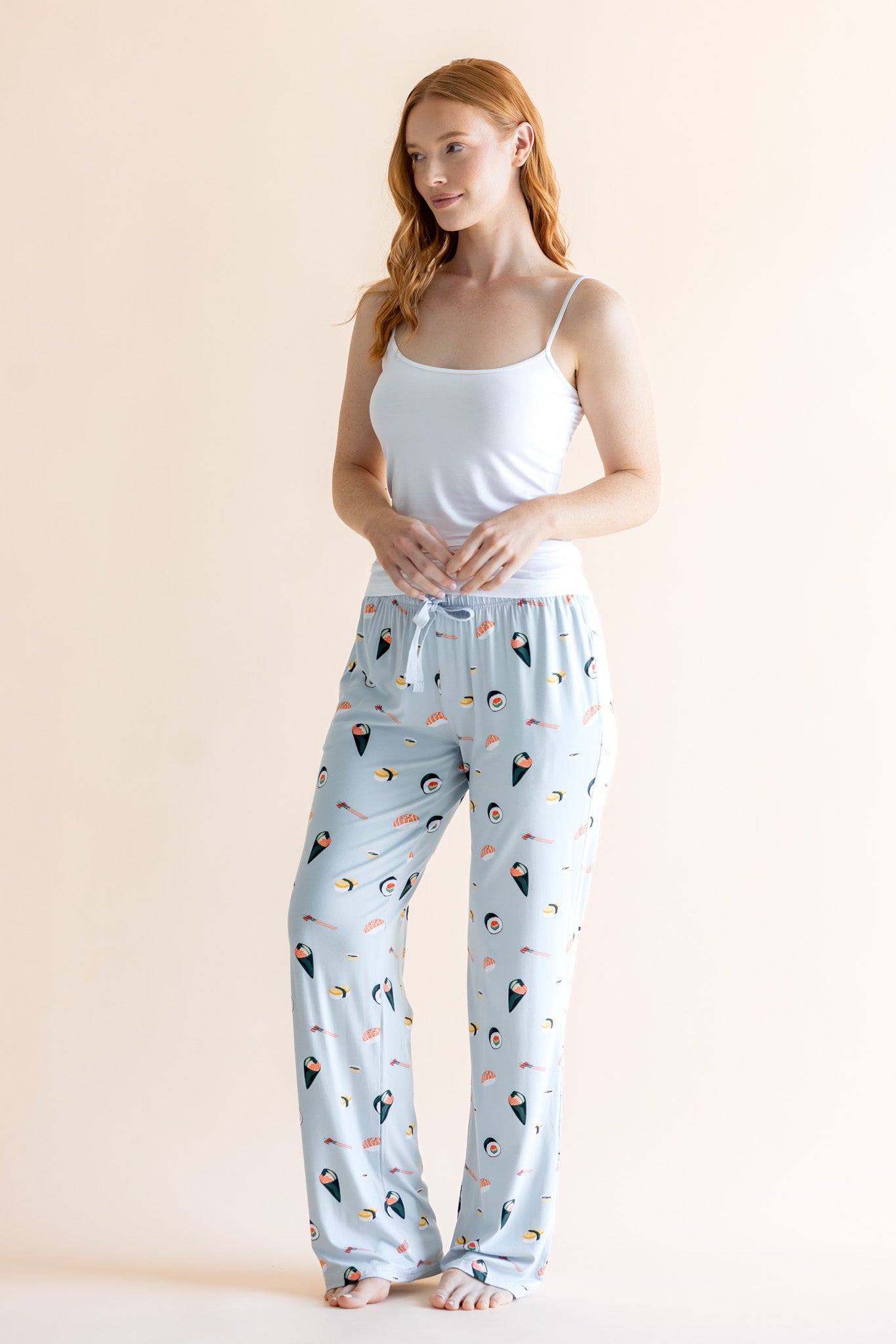 Model wearing blue Women's Lounge Pants with Sushi print under white camisole on a beige background