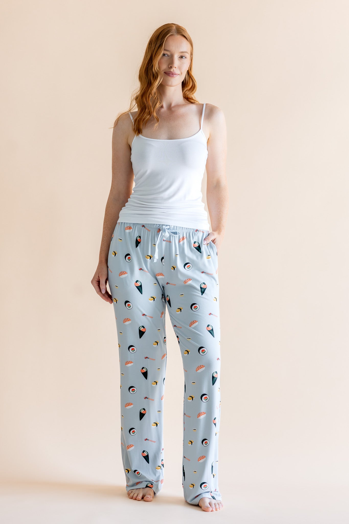 Model in blue Women's Lounge Pants in Sushi print under white camisole on a beige background