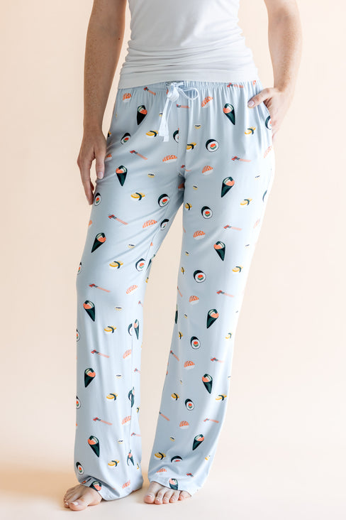 Model showing pockets of blue Women's Lounge Pants with drawstring in Sushi print under white camisole on a beige background