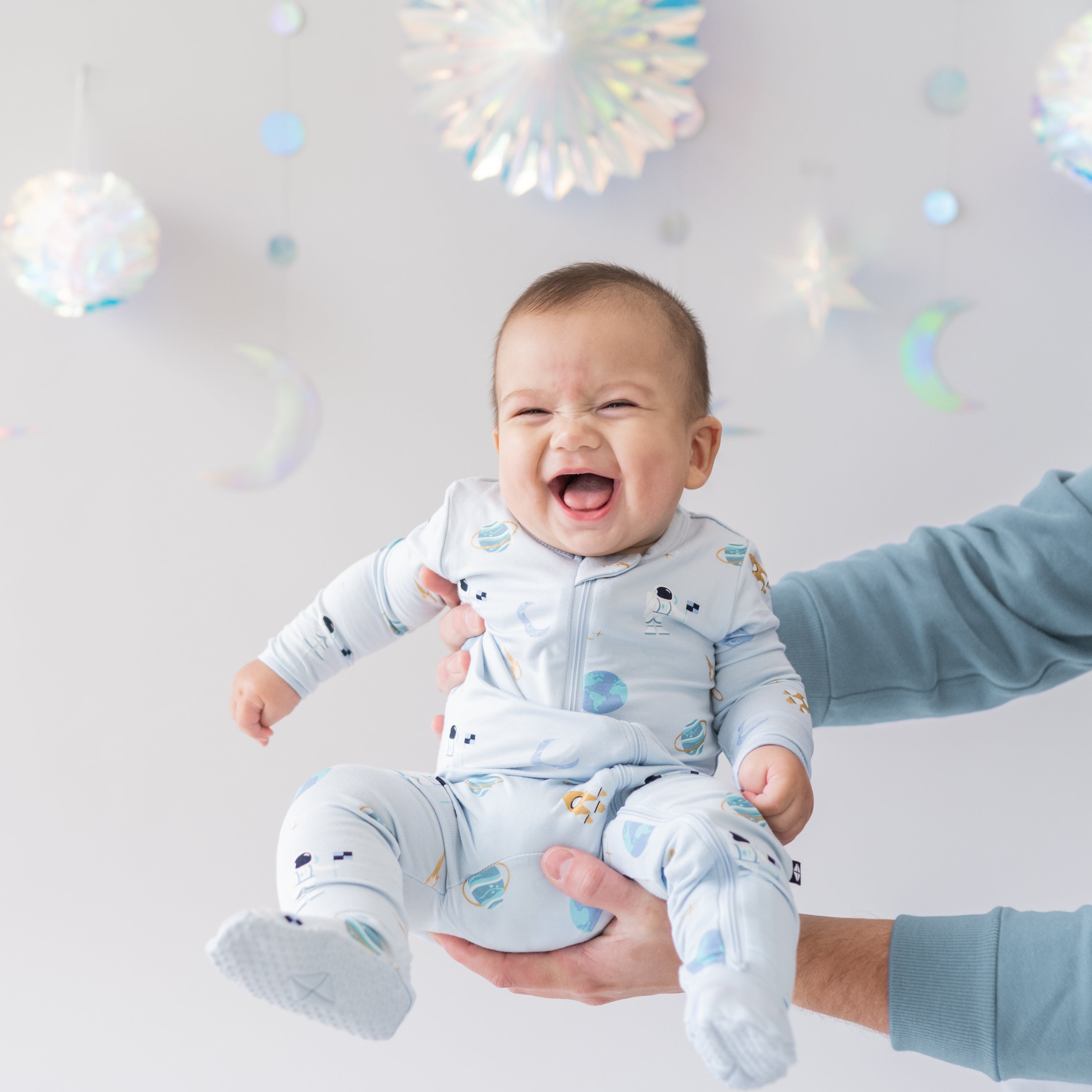 baby smiling being held wearing ice space zippered footie