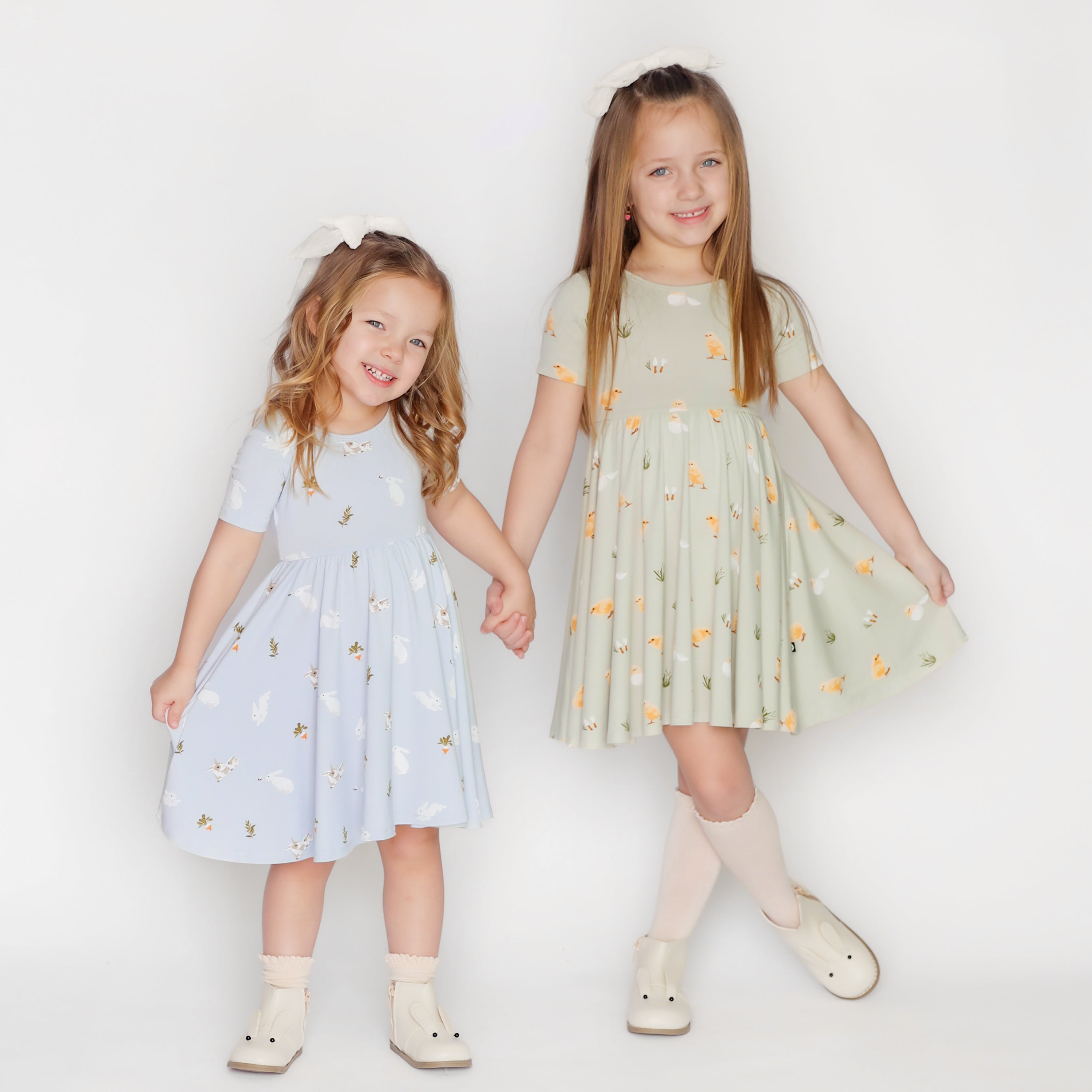 2 girls holding hands wearing kyte baby twirl dresses in easter prints