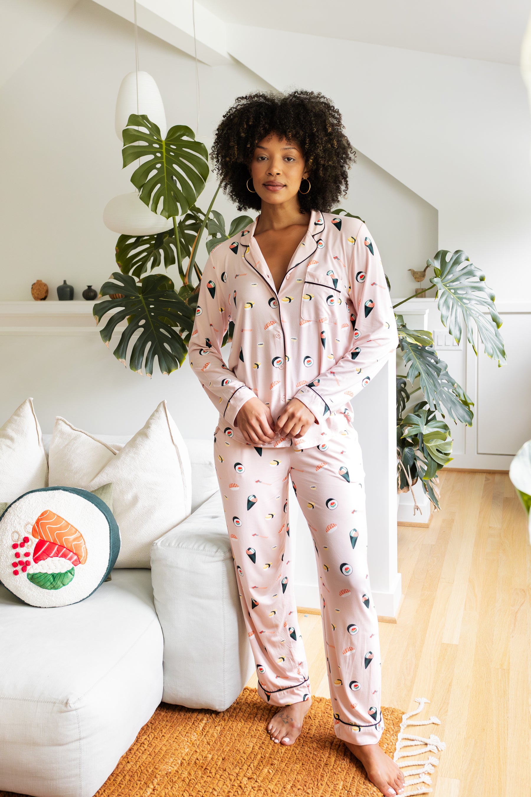 Woman wearing a pink pajama set with a sushi pattern in a living room.