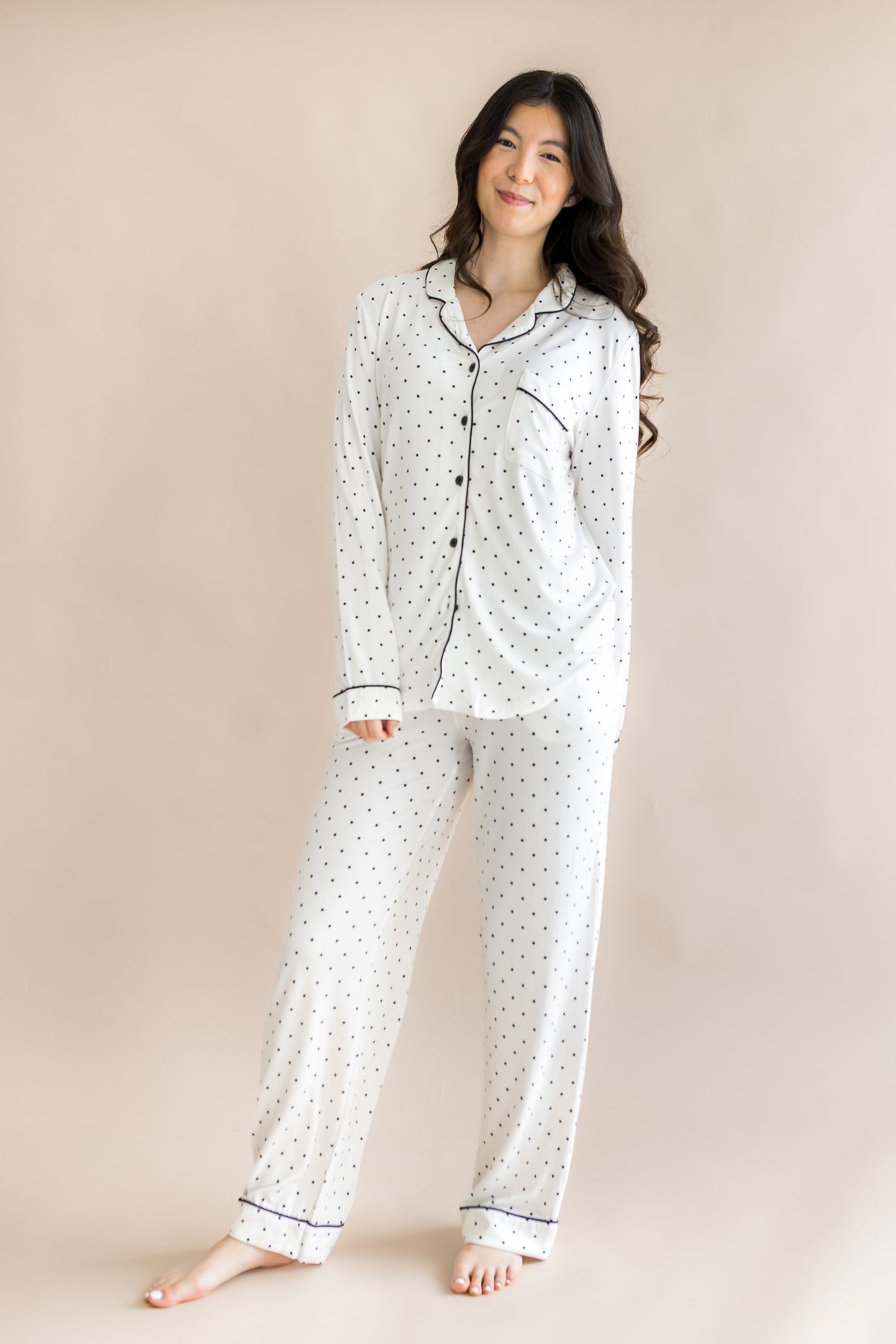 Model wearing Midnight Polka Dot print Women's long sleeve pajama set on a beige background