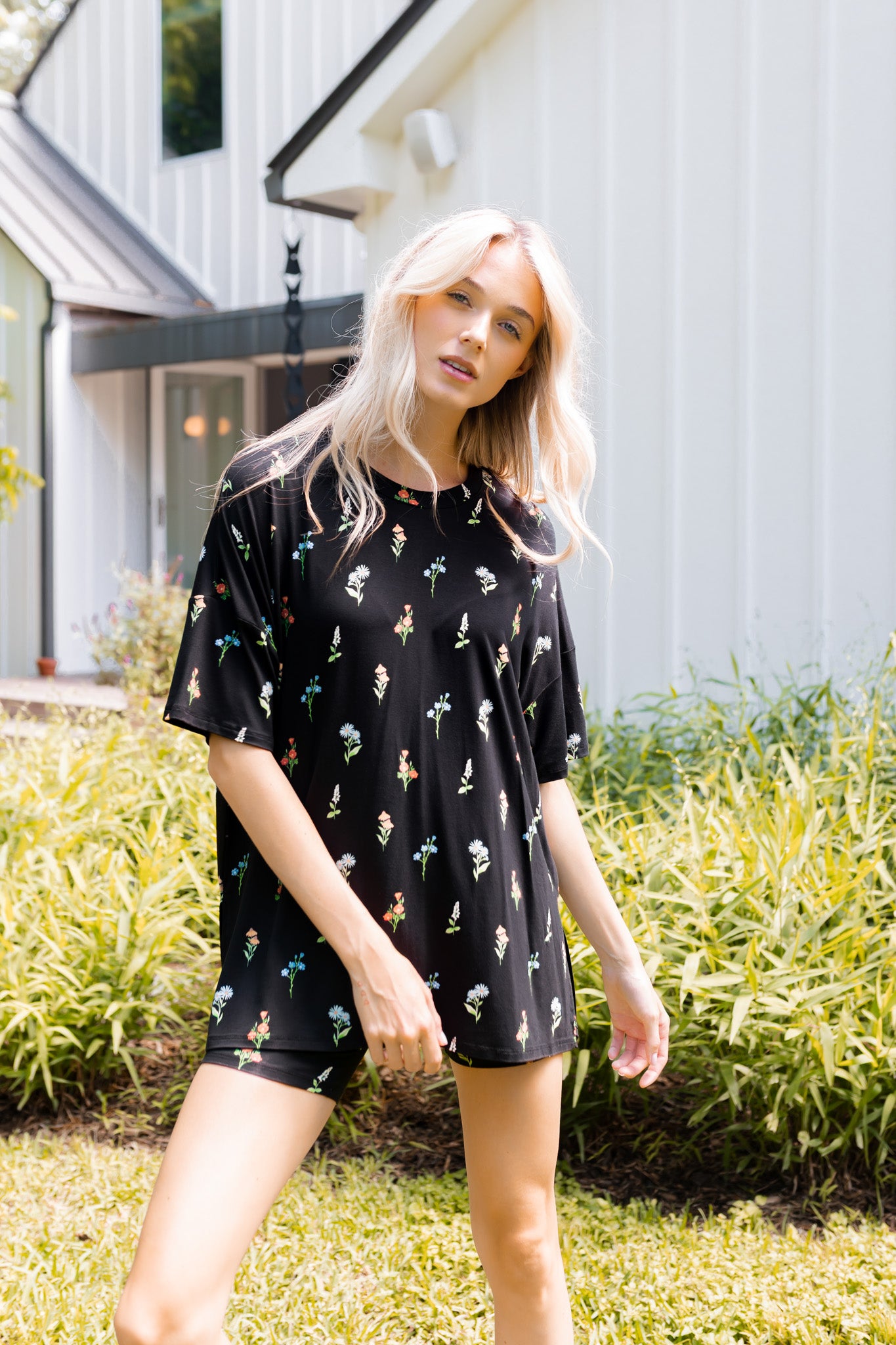 Model wearing Women’s Biker Short Set in Midnight Wildflower print outdoors in sunlight with bushes in the background
