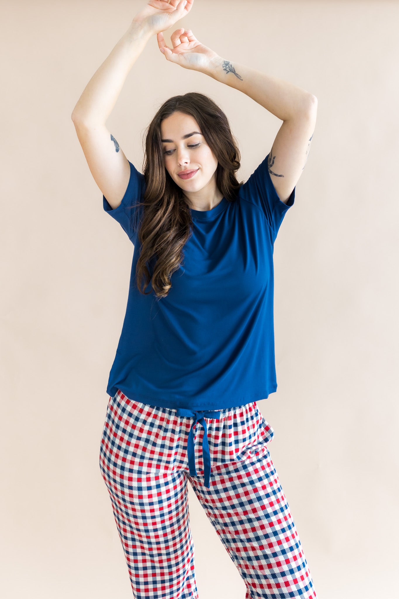 Model wearing red blue and white Patriotic Gingham check print women's lounge pants under a navy shirt on a beige background