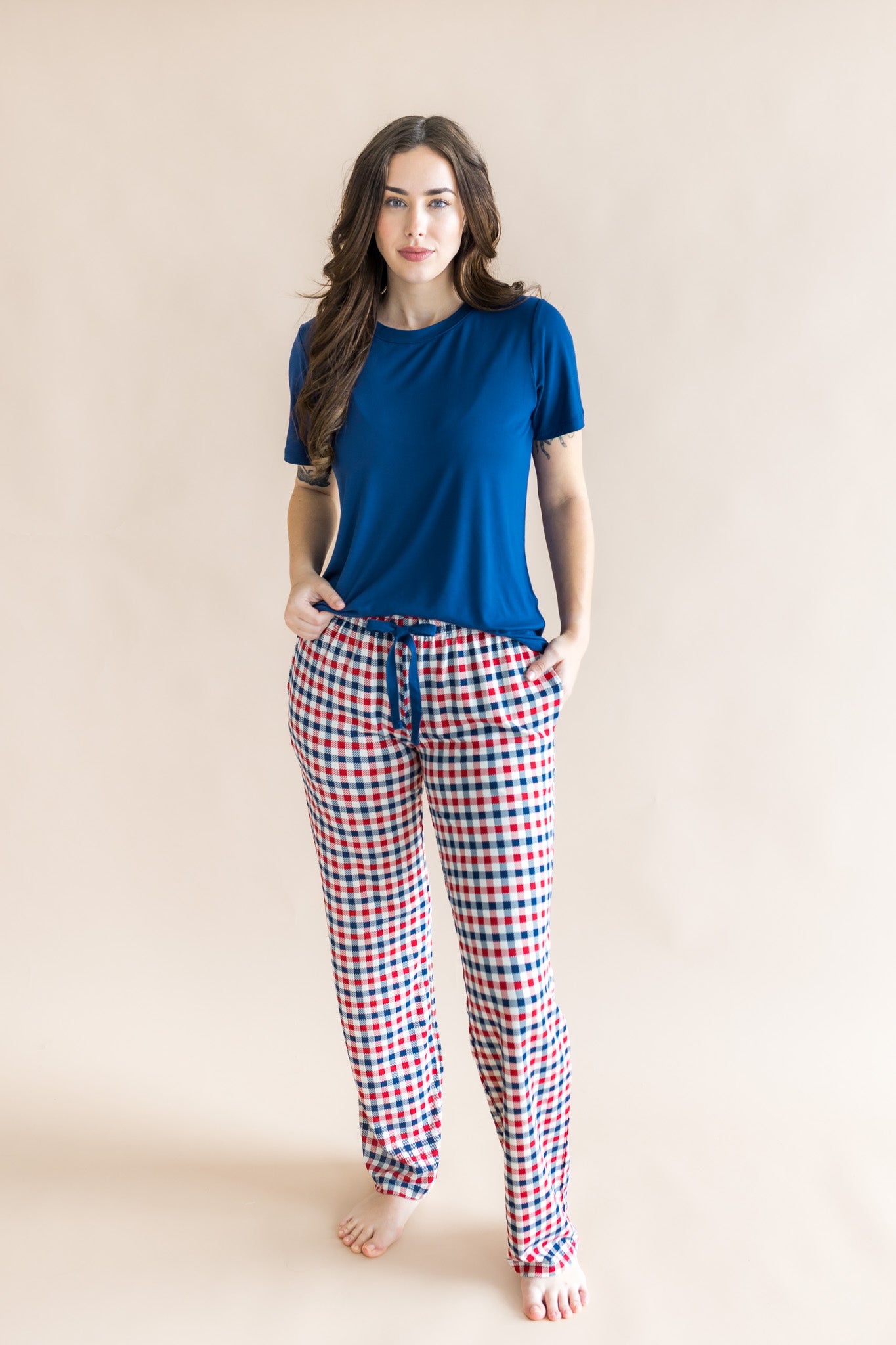 Model wearing red blue and white Patriotic Gingham check print women's lounge pants under a tahoe shirt on a beige background
