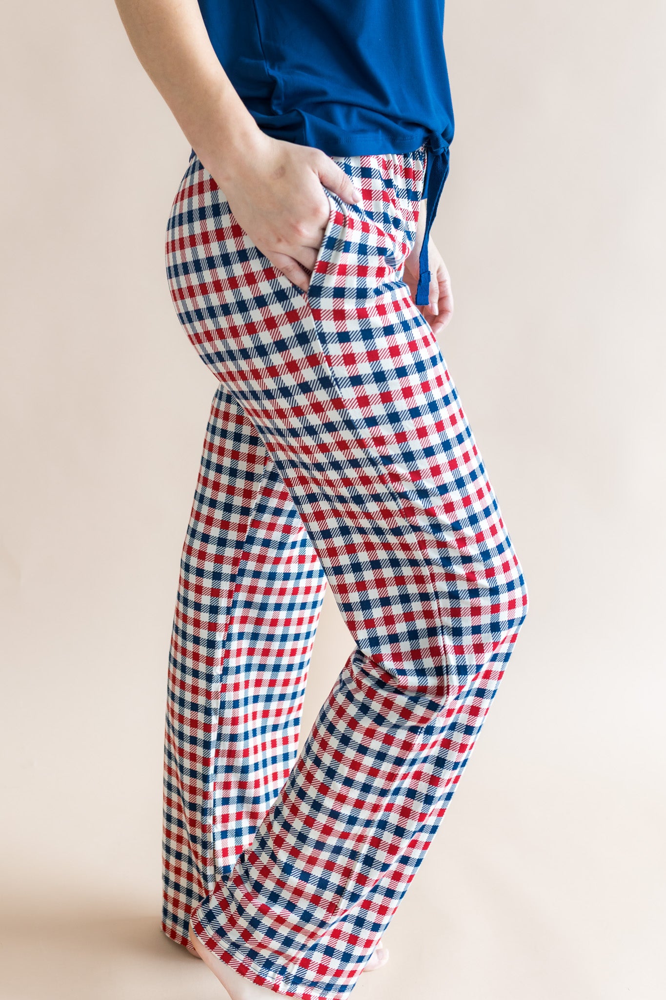 Side view women's lounge pants with pockets in red blue and white Patriotic Gingham print under a Tahoe shirt on a beige background