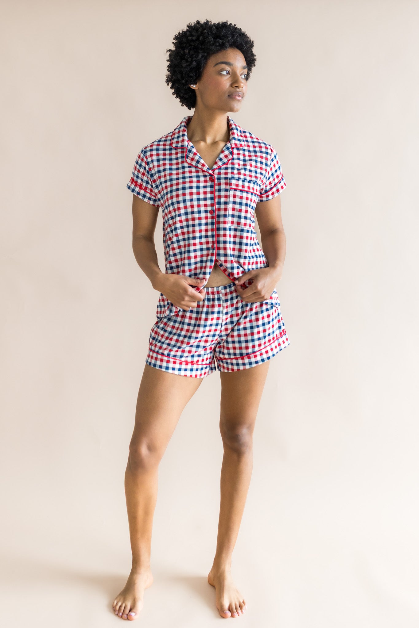 Model in women's short sleeve pajama set in red blue and white Patriotic Gingham check print on a beige background