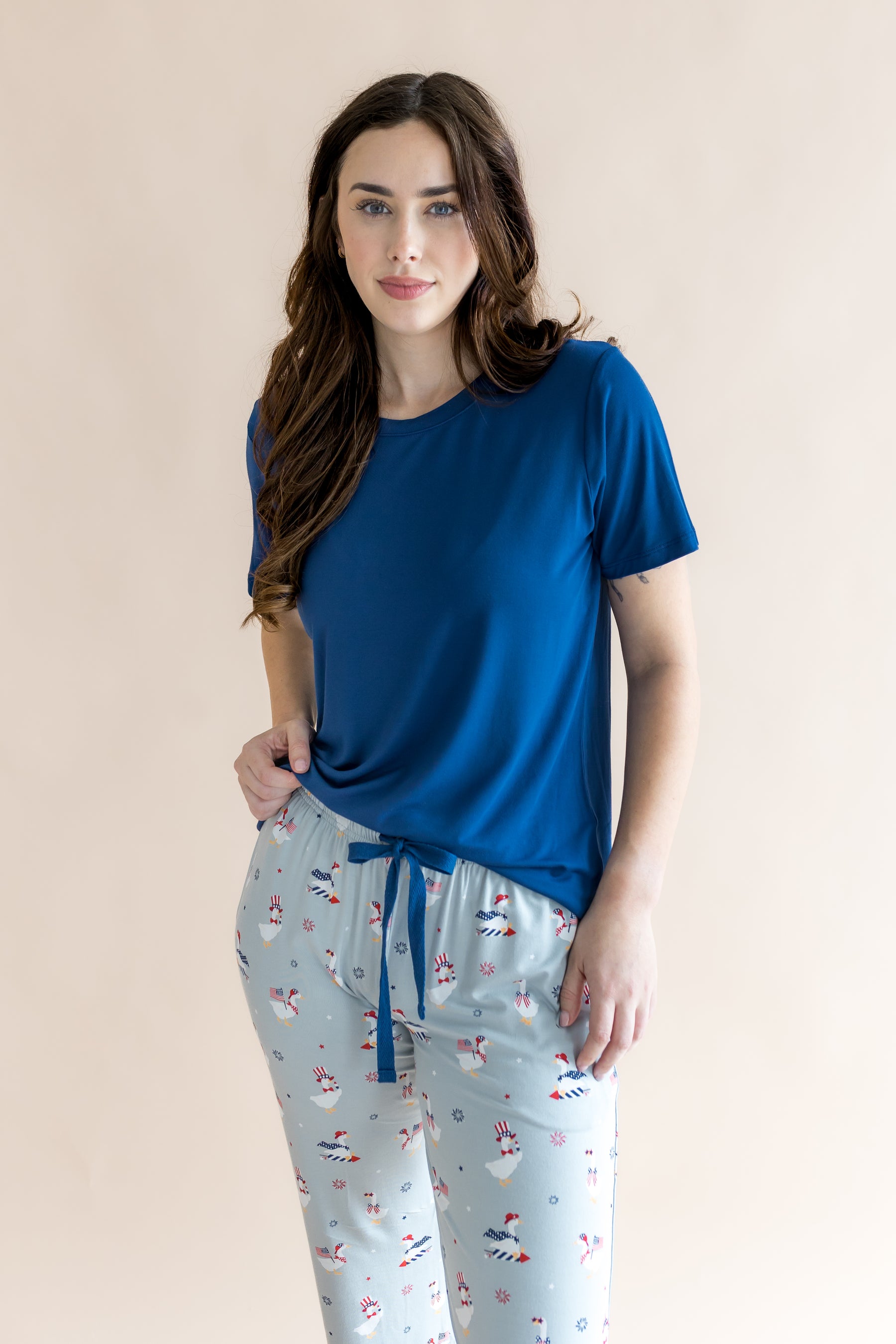 Model wearing Light blue women's lounge pants in Patriotic Goose print under a tahoe shirt on a beige background