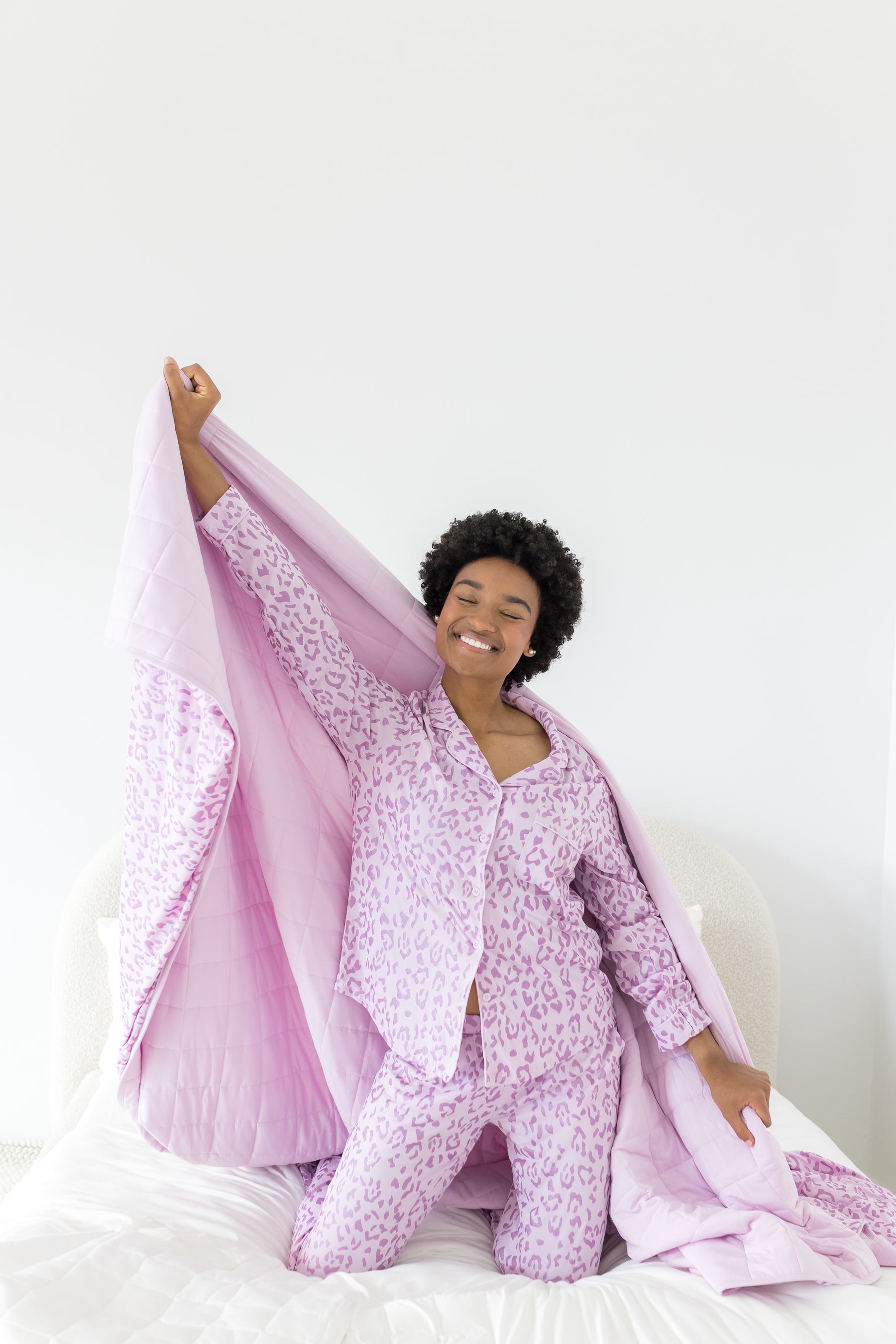 Model posing with Adult Blanket in Thistle Leopard print wearing similar print long sleeve pajamas on a white background