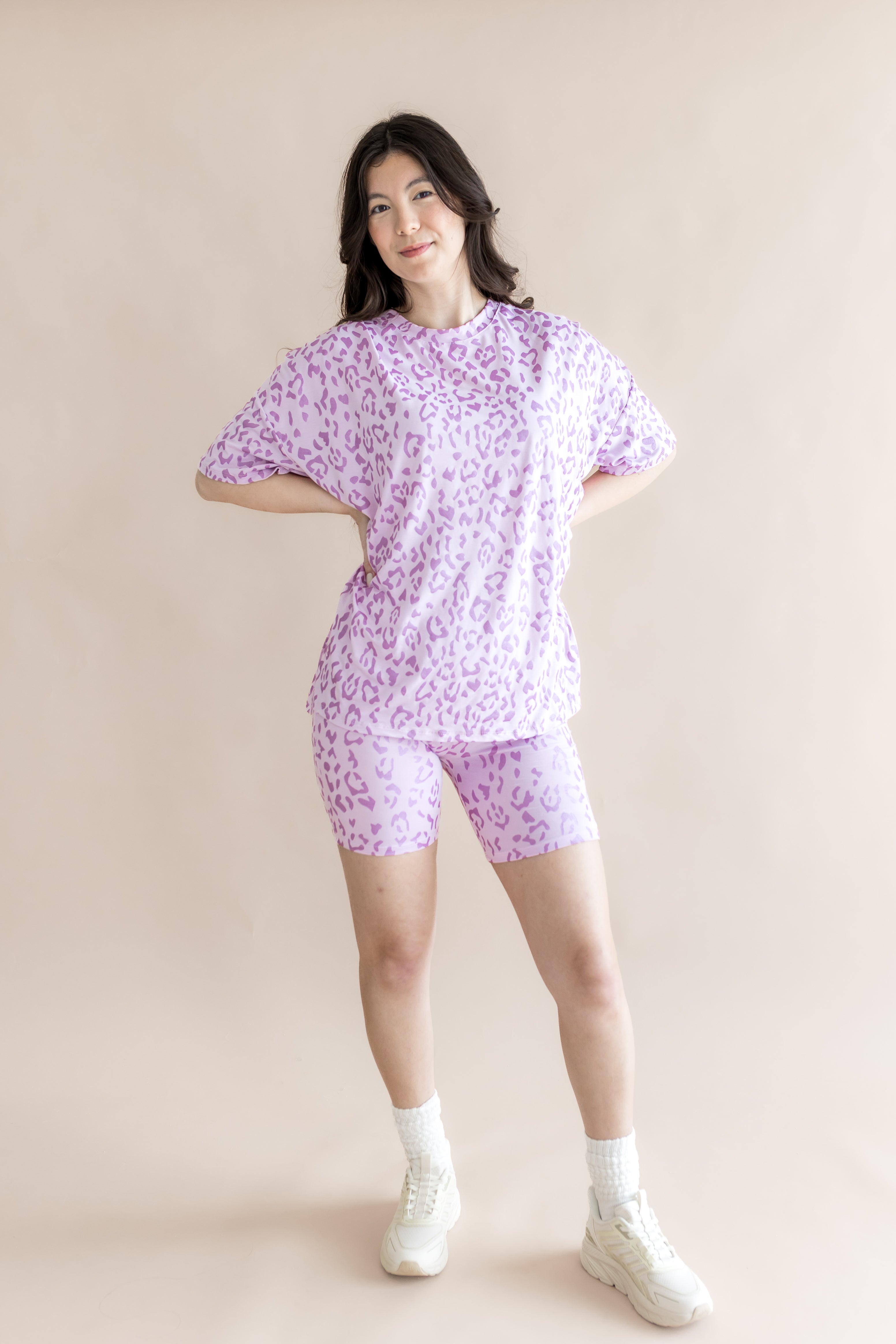 Model posing in Thistle Leopard print  Women’s Biker Short Set with white socks and shoes on a beige background