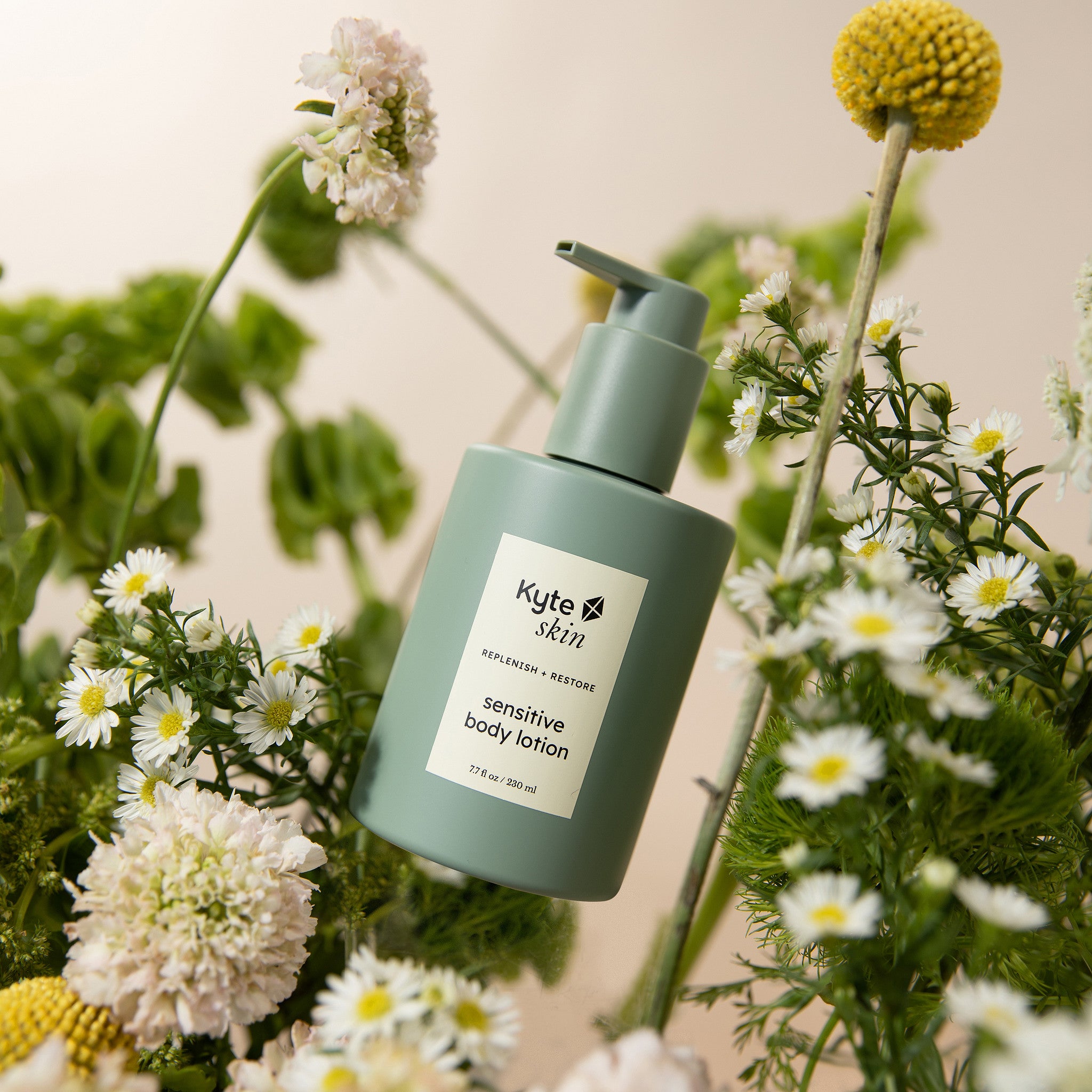 Green bottle of Kyte Skin sensitive body lotion surrounded by flowers