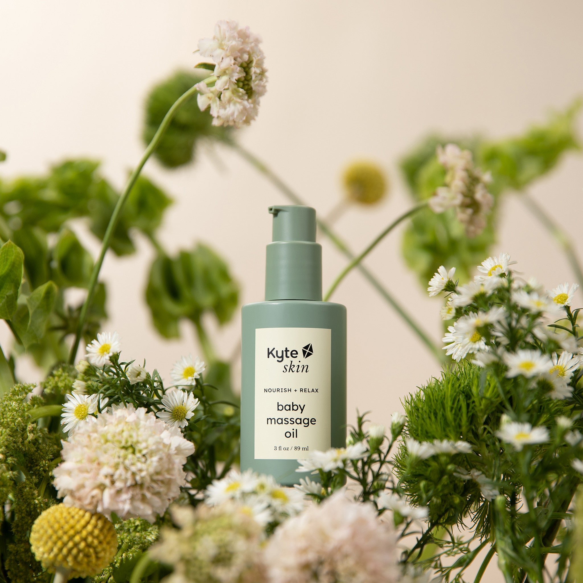 Kyte Skin baby massage oil bottle surrounded by flowers and greenery