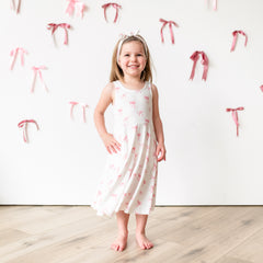 Child modeling Tank Twirl Dress in Bow with a bow background