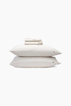 Stack of champagne pillows and folded sheets on a white background