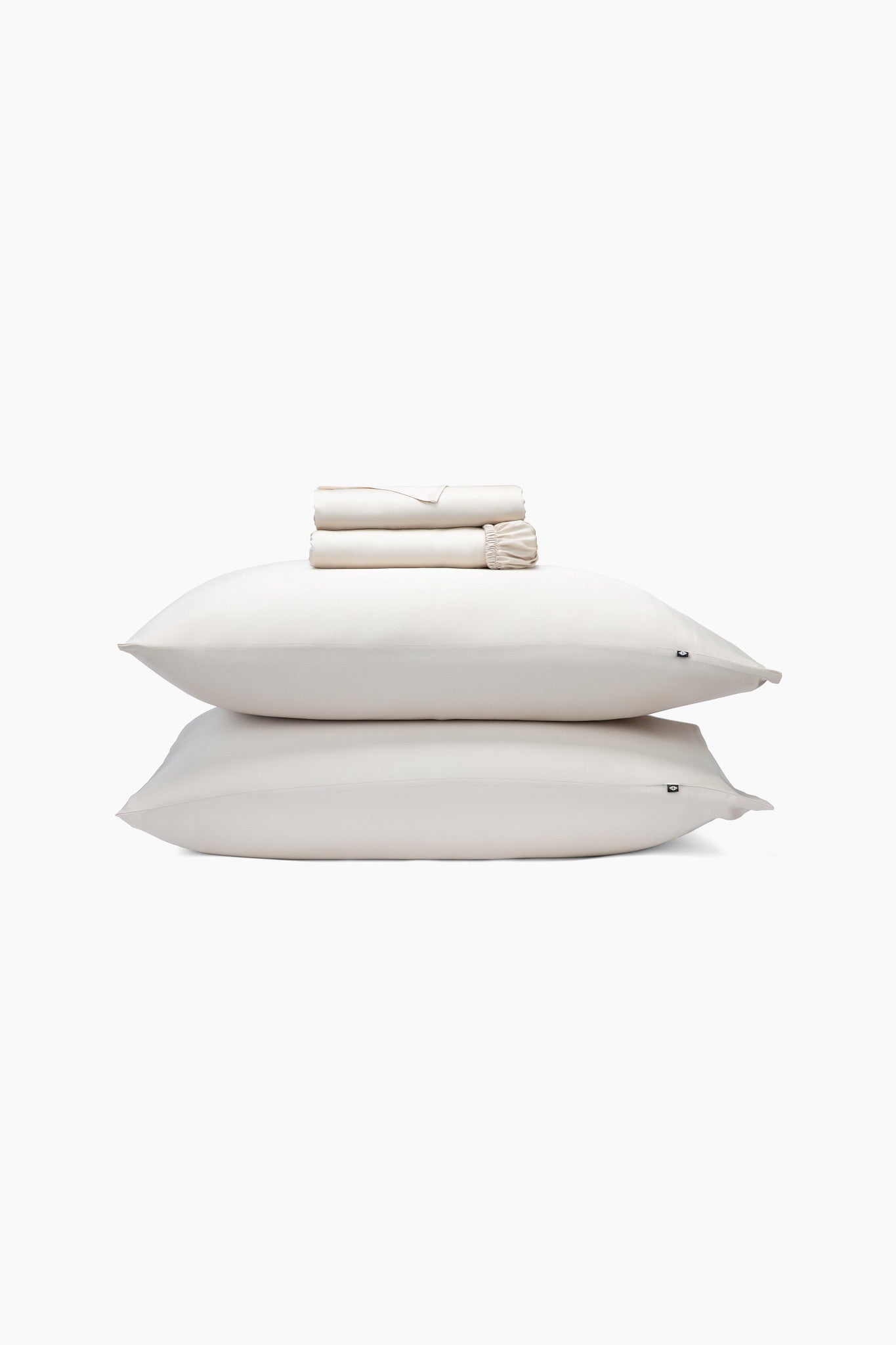 Stack of champagne pillows and folded sheets on a white background